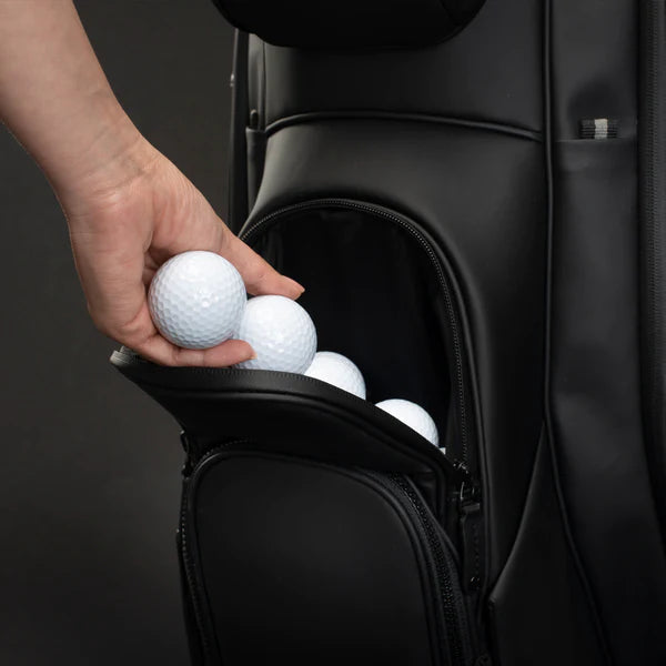 A model placing golf balls into the upper ball pocket of a black lux cart bag