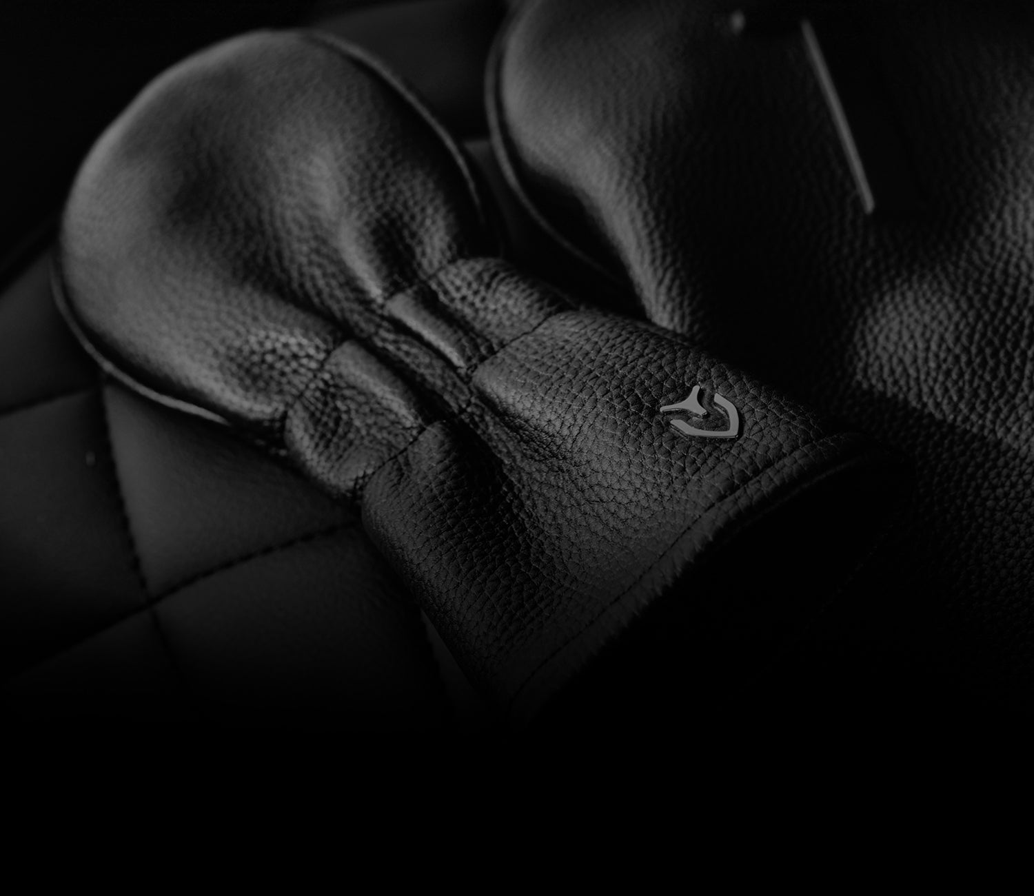 Two pebbled black leather golf headcovers on quilted leather seat