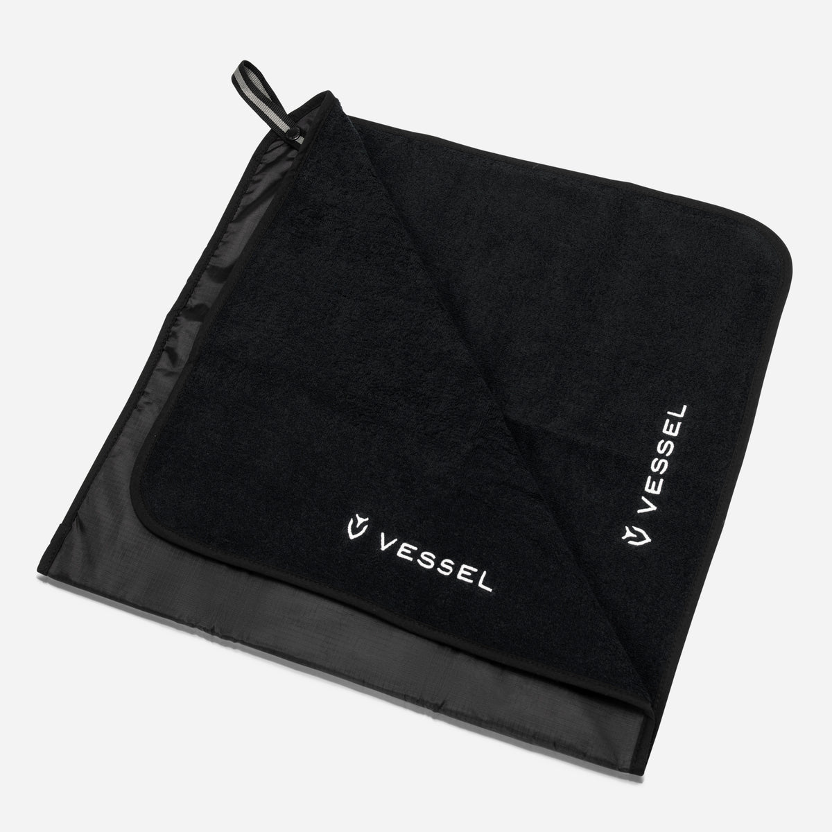 A black golf rain hood towel with the VESSEL brand logo visible on it.