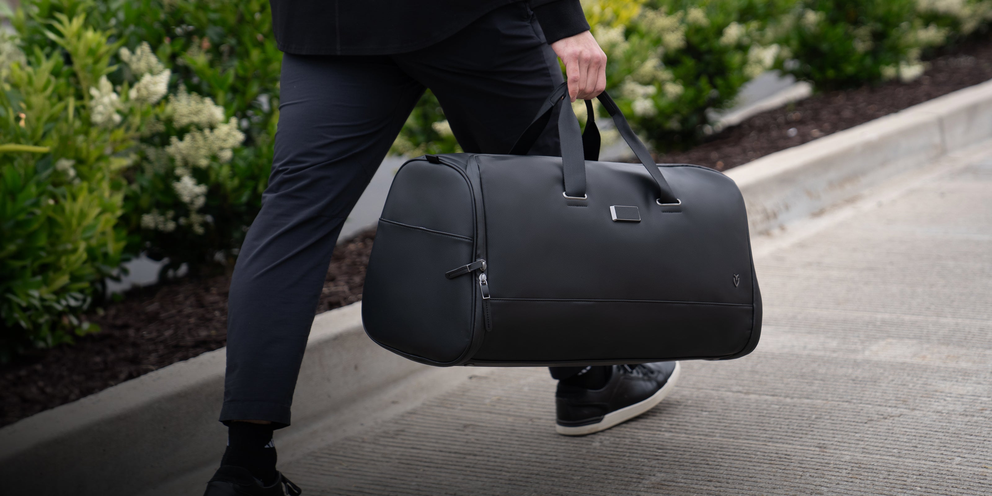 Model carrying black signature garment duffel