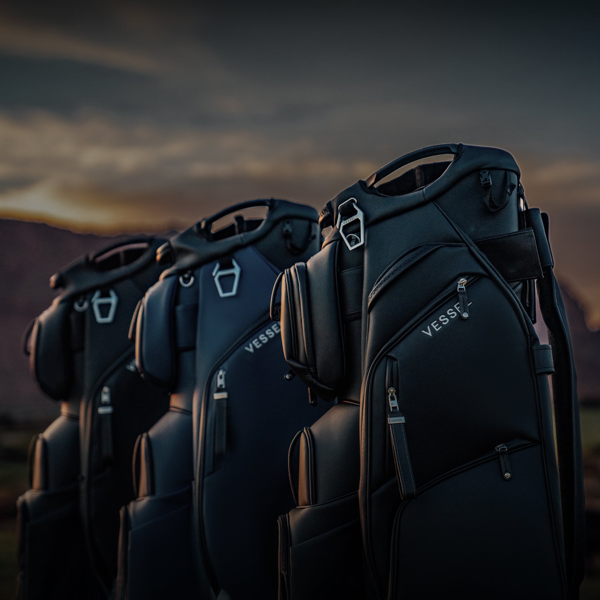 Three golf cart bags lined up in a sunset background