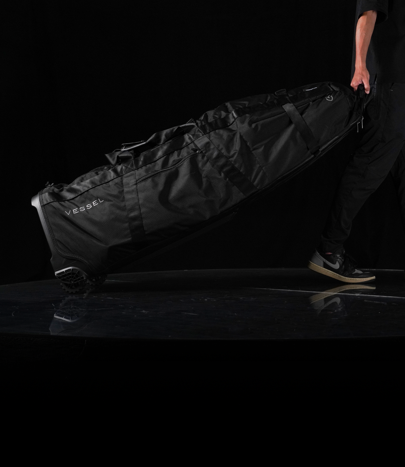 Man rolling travel case across a black stage