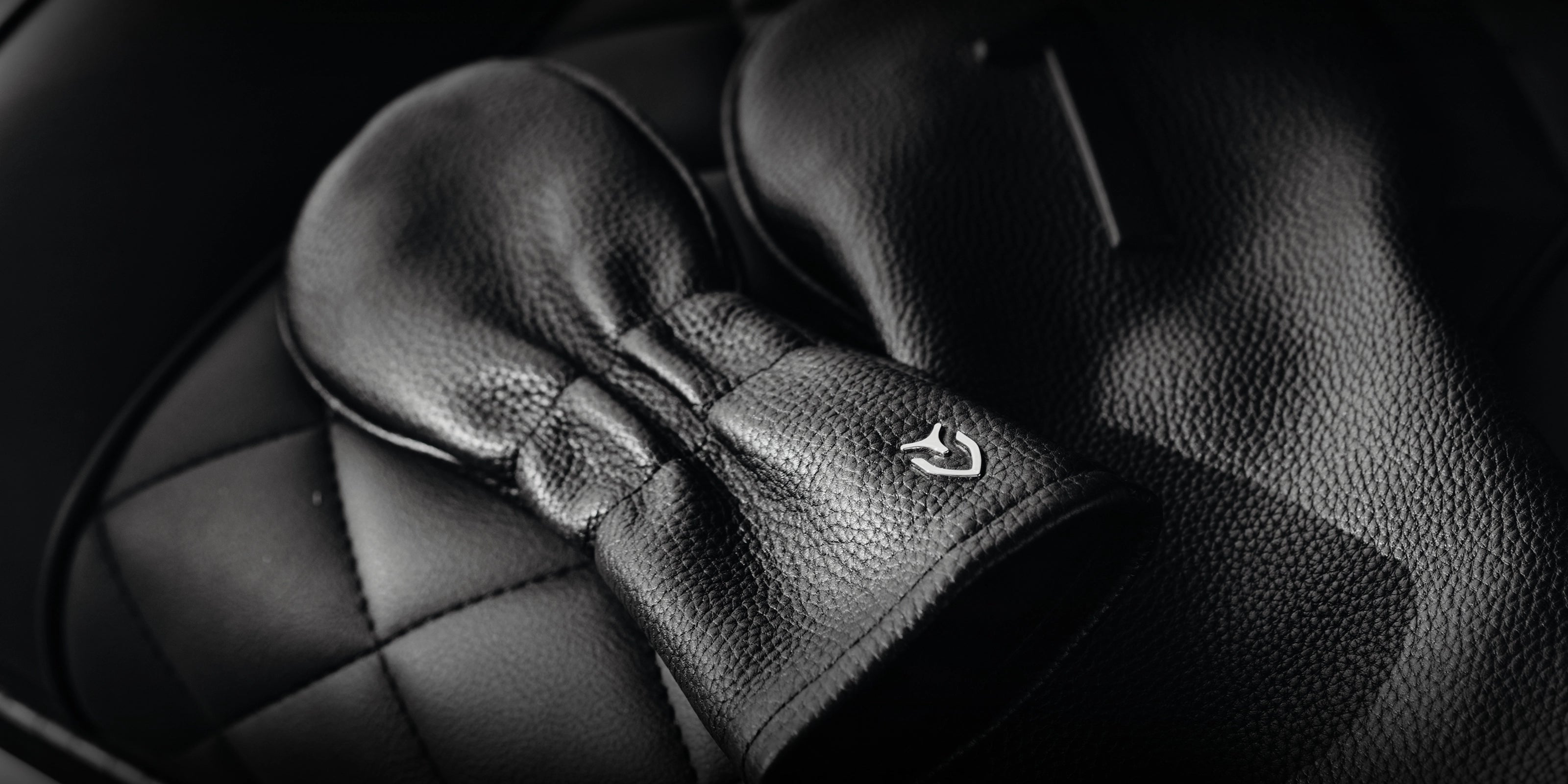Two pebbled black leather golf headcovers on quilted leather seat