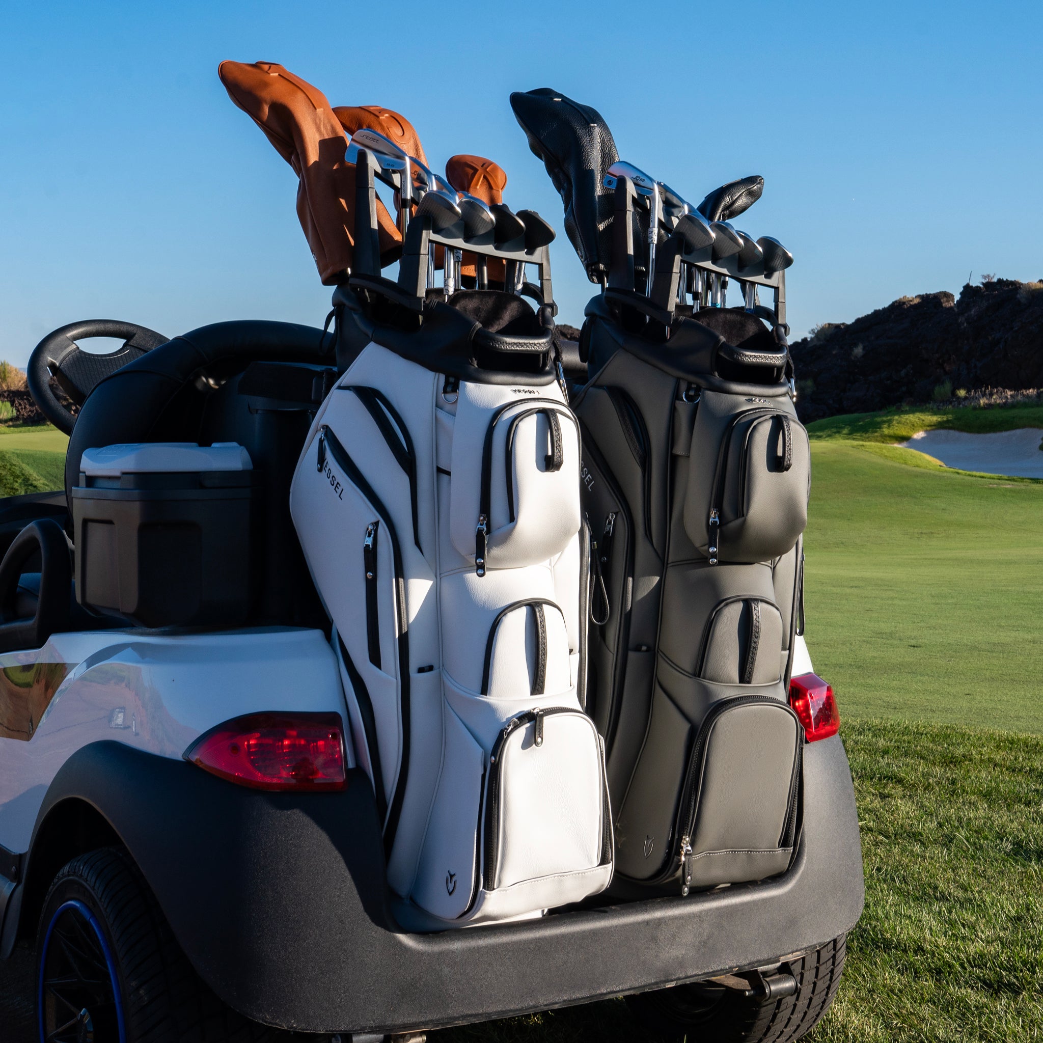 Two golf bags with clubs on a golf cart on a golf course