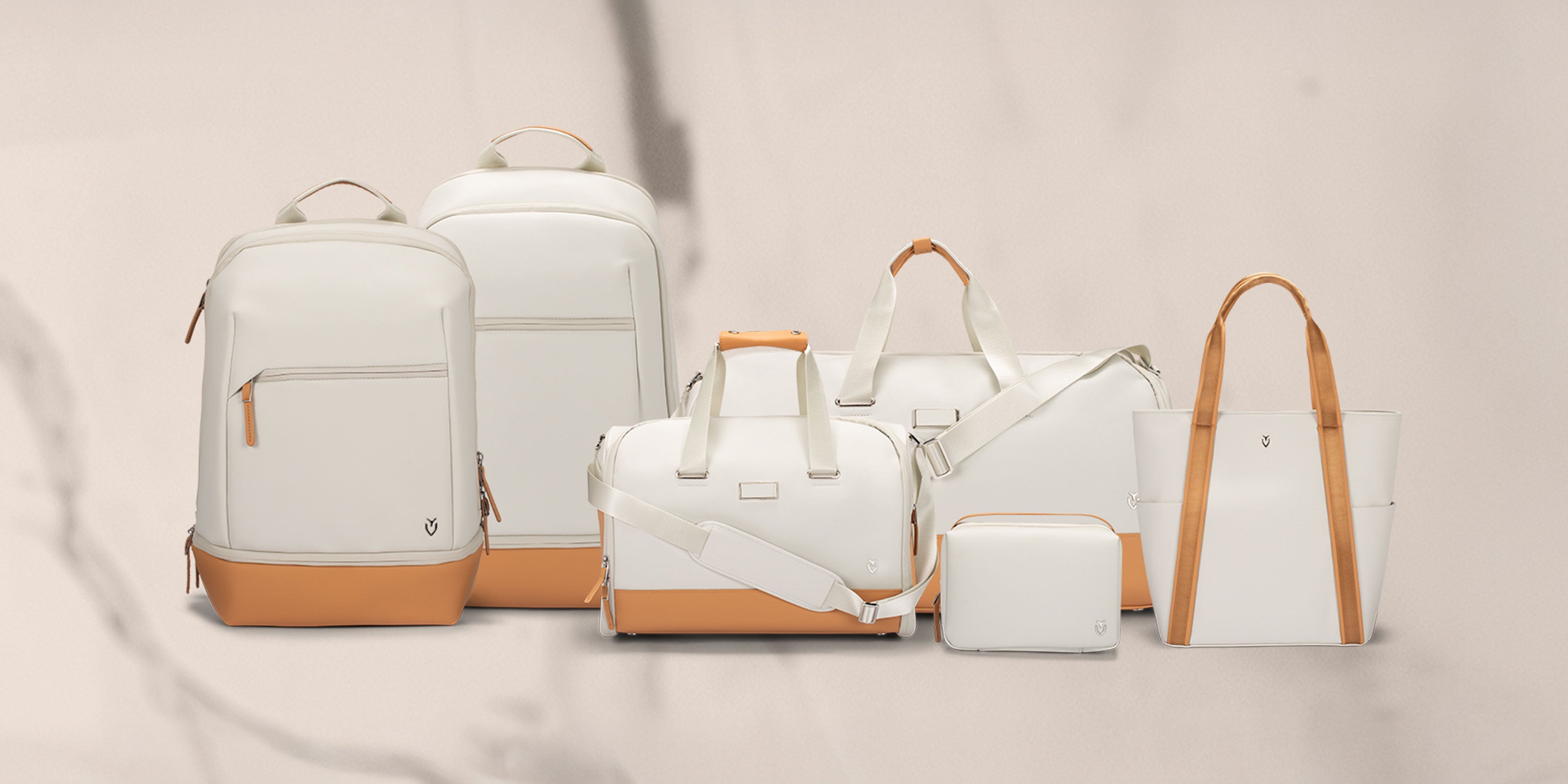 6 white and latte bags next to each other: Signature Backpack, Signature Plus Backpack, Signature Weekender, Signature Garment Duffel, Lux Toiletry, Signature Tote