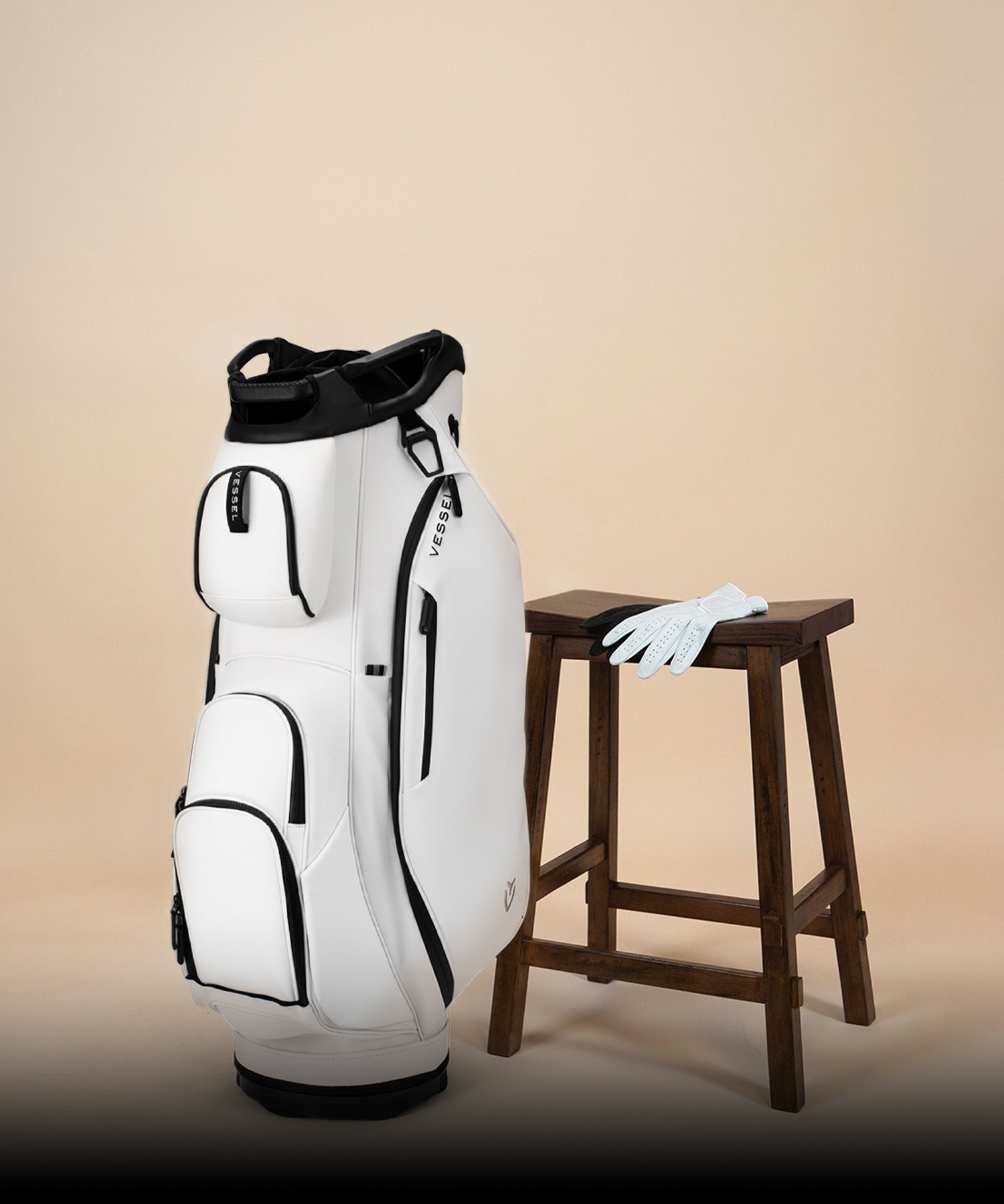 White Lux Cart next to two leather golf gloves and wooden stool