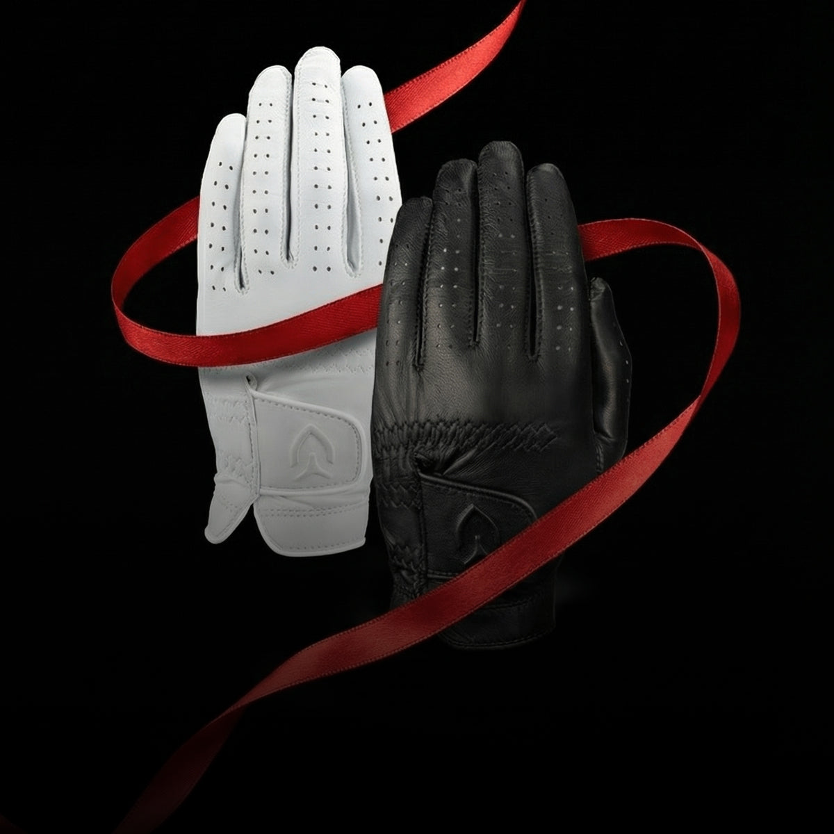 A black leather golf glove and a white leather golf glove wrapped loosely in red ribbon