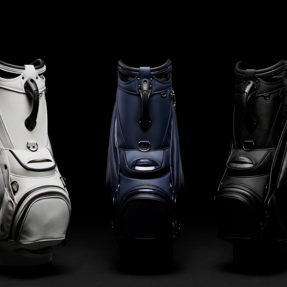 White staff bag, navy staff bag and black staff back in a row in a black studio