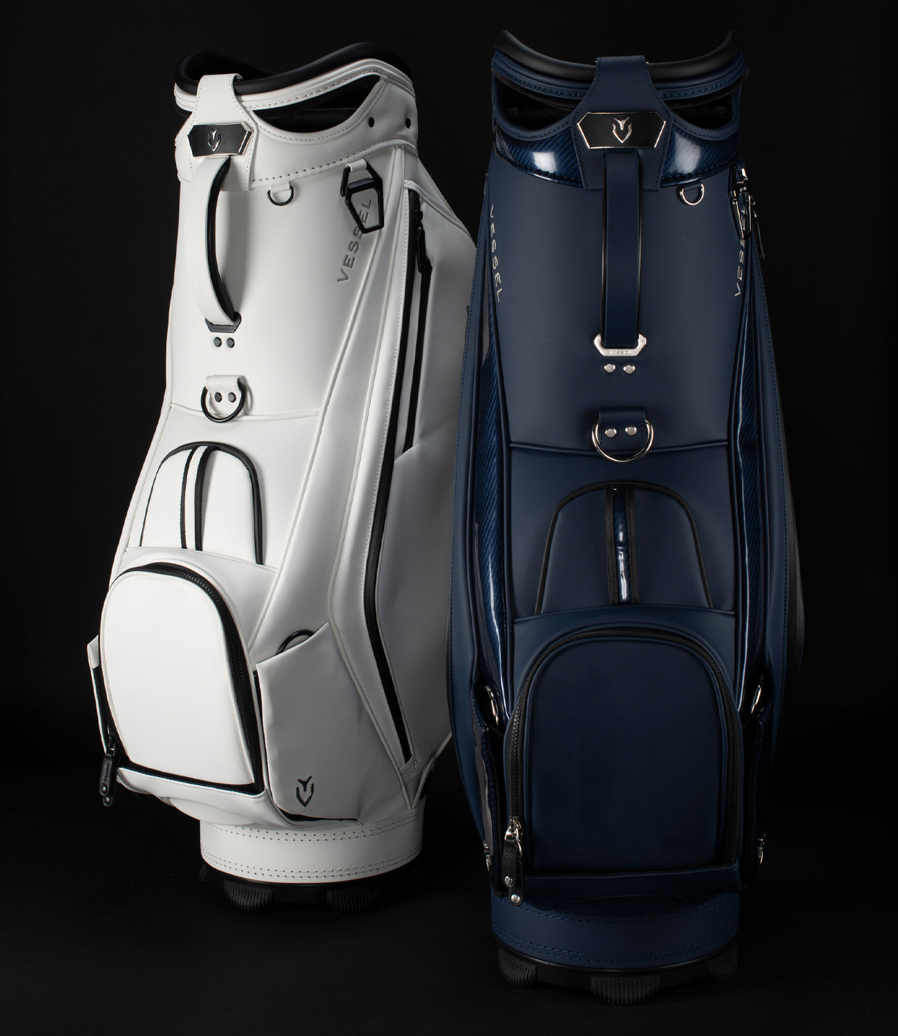 White staff bag and a navy staff bag next to each other in black studio