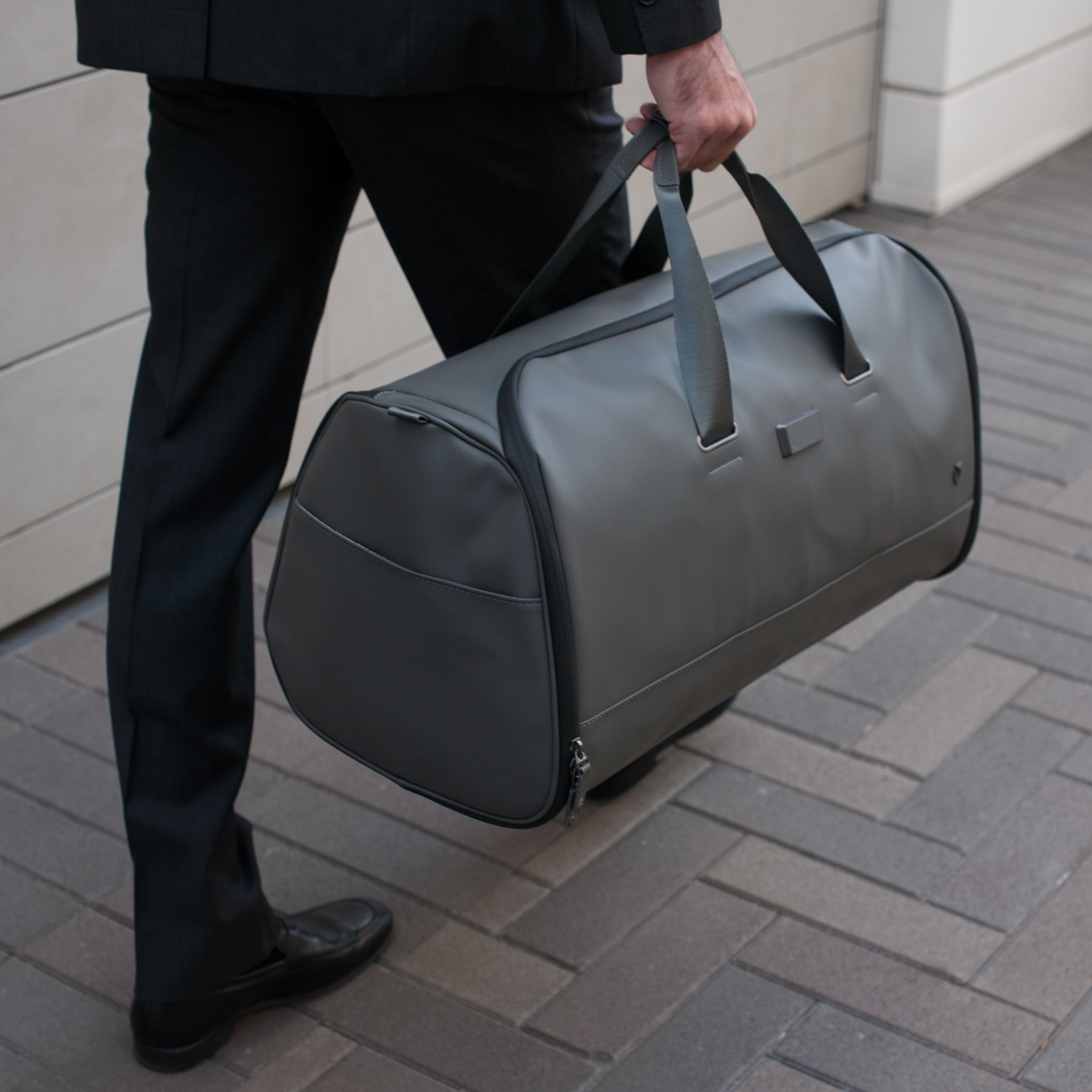 Grey signature garment duffel being carried #color_pebbled grey