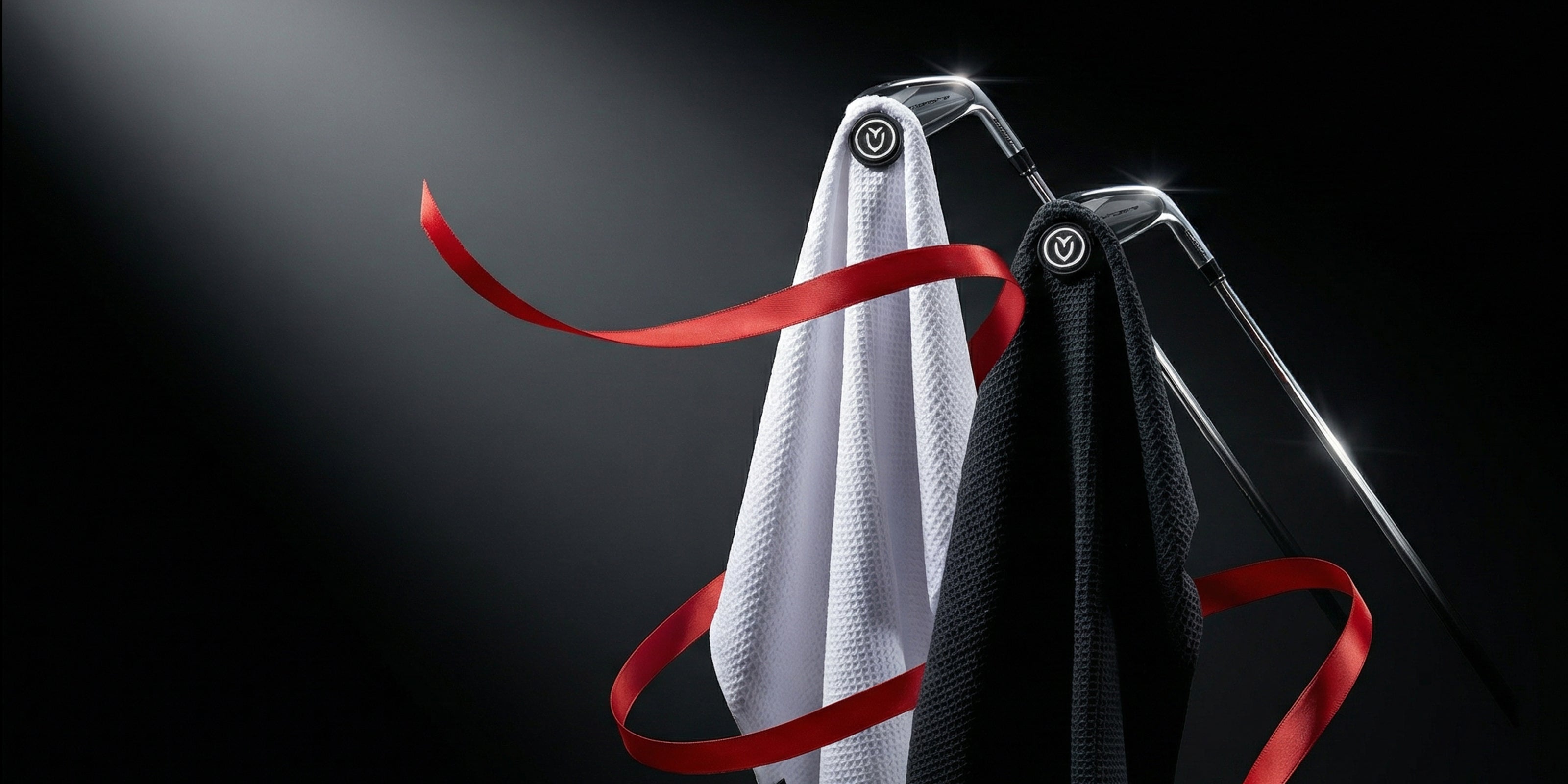 A White and a black magnetic golf towel wrapped loosely in red ribbon