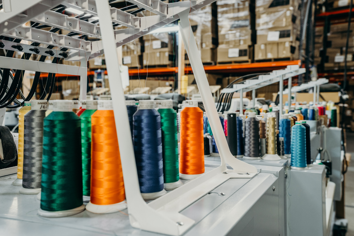 Many rolls of colored thread on top of embroidery machine in a warehouse