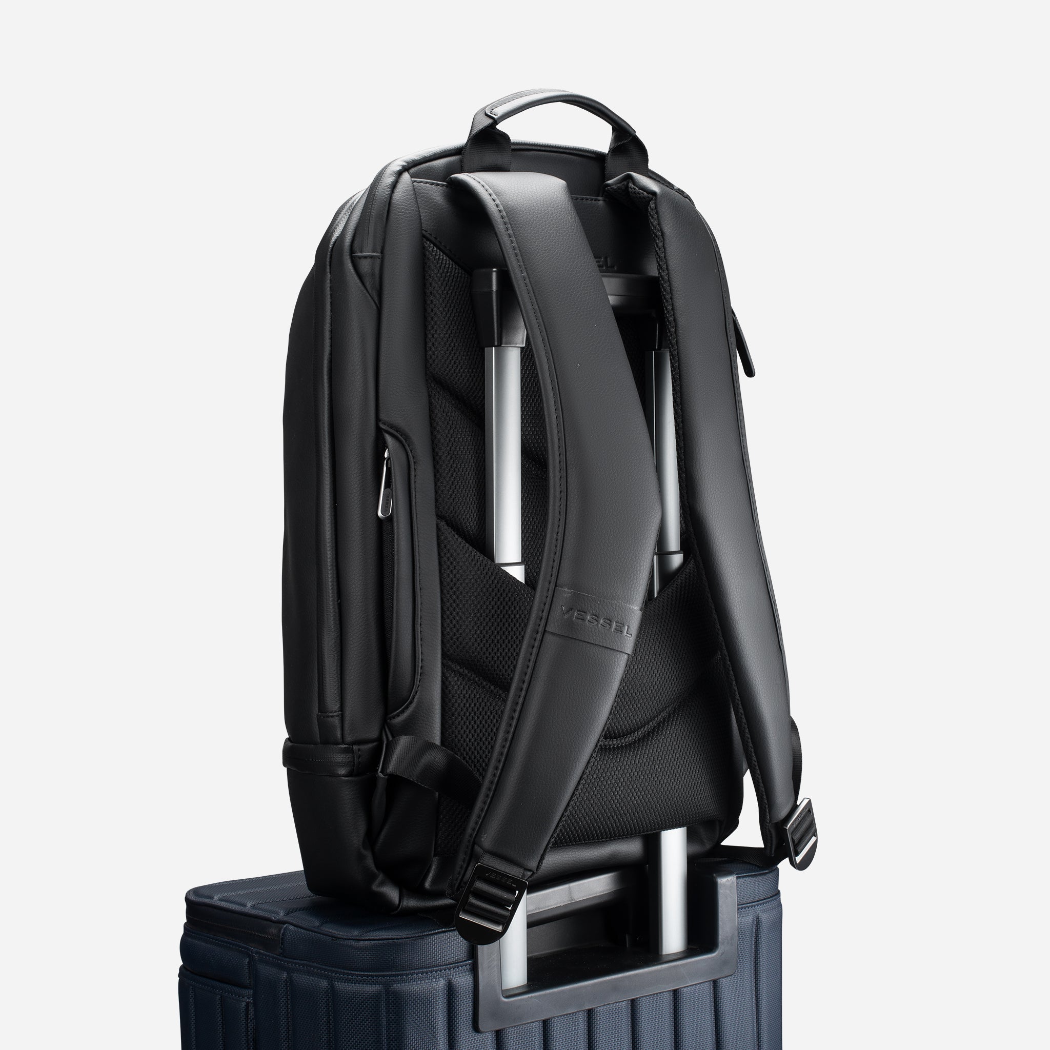 Pebbled Black Signature Backpack sitting on top of suitcase #color_pebbled black