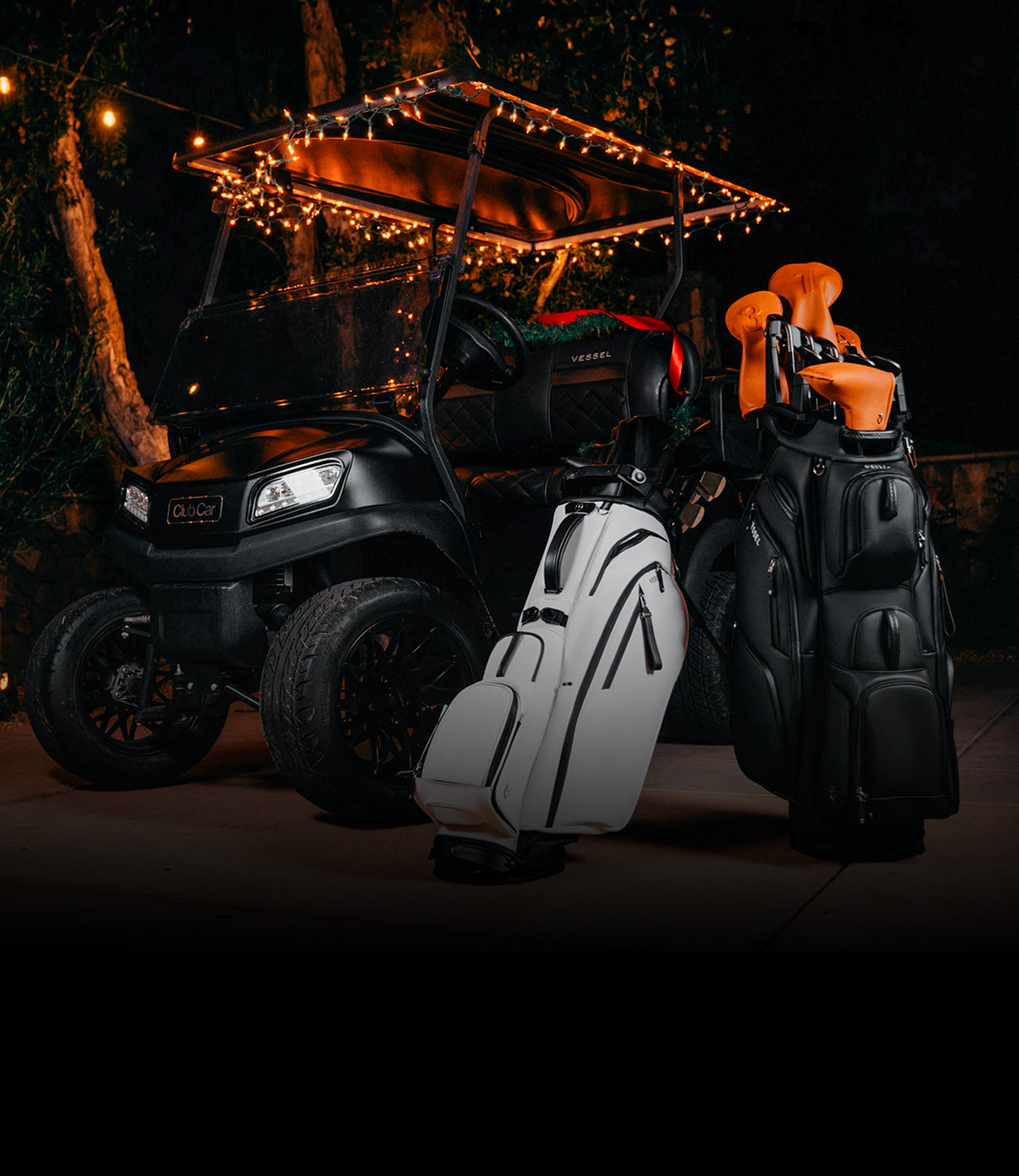 White Player V Pro and Black Lux Pro Cart II bags next to golf cart, Christmas decor