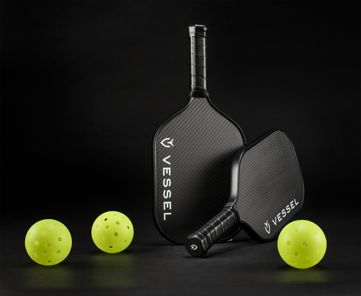 black carbon pickleball paddles next to pickleballs