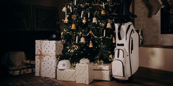 Gifts and a golf stand bag around a lighted christmas tree
