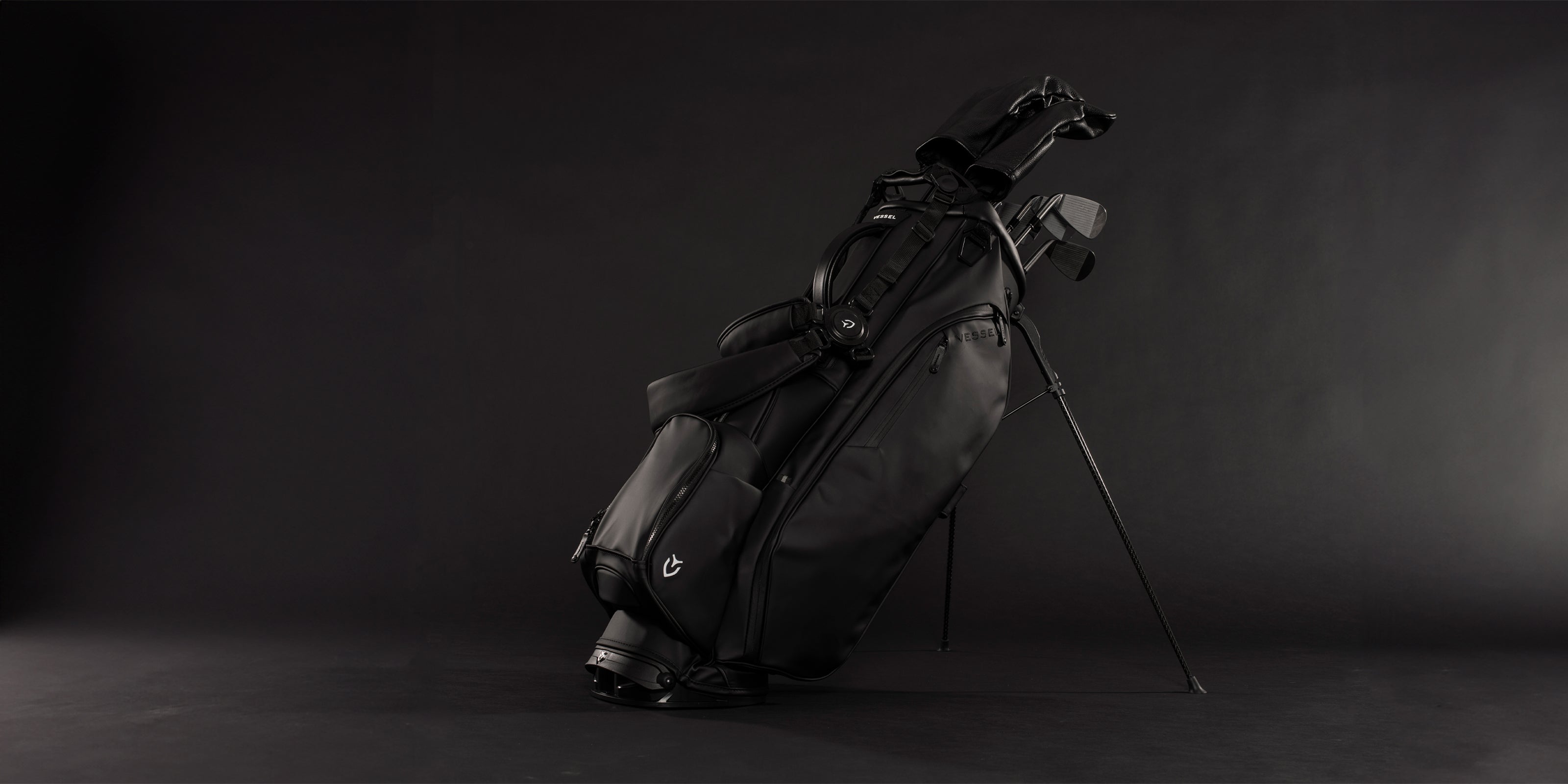 Black golf stand bag with golf clubs with headcovers in black studio