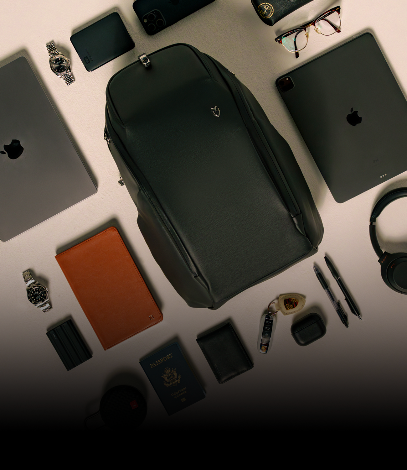 Black travel backpack with everyday items laying around it