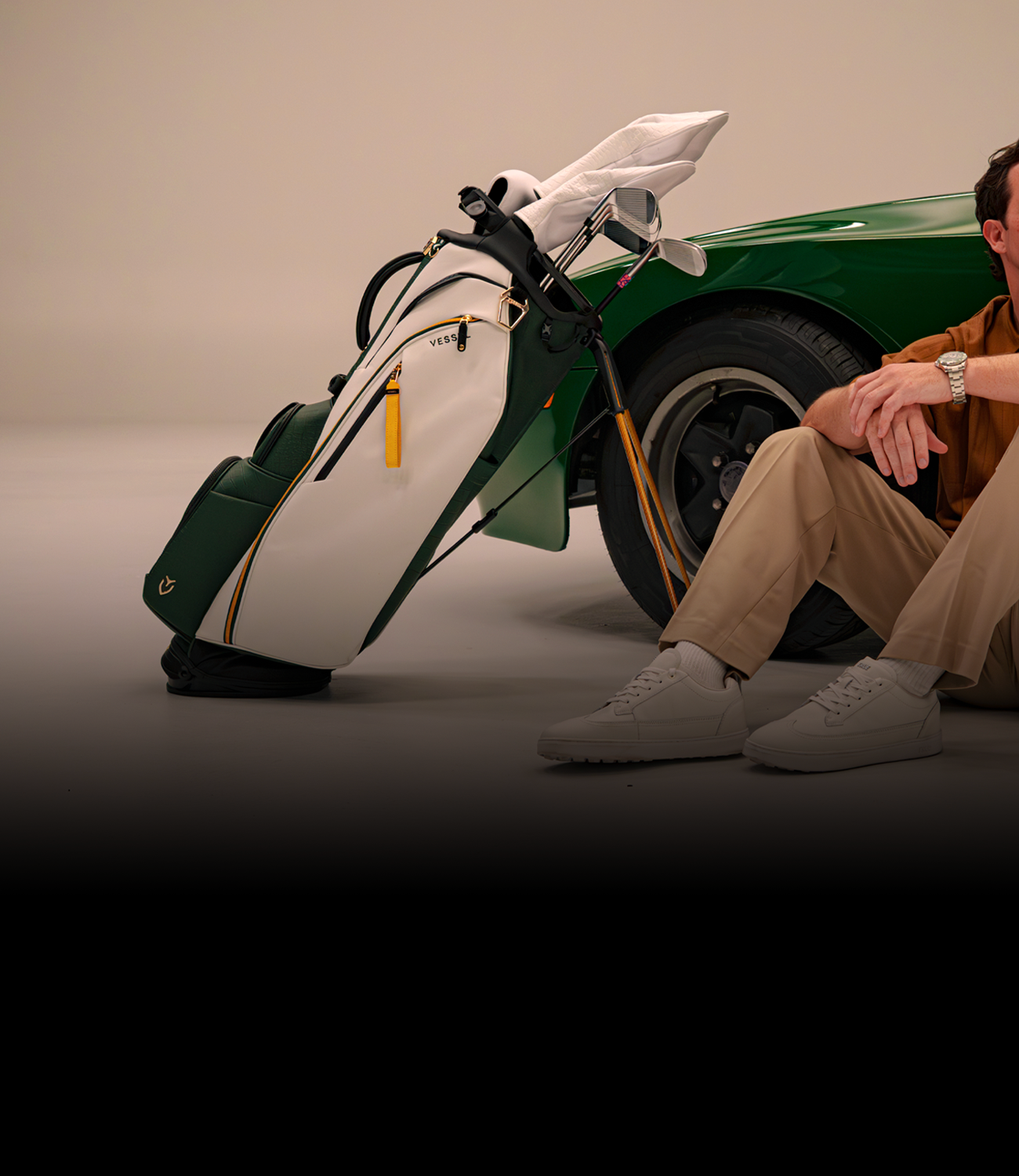 Man sitting next to Season Opener 2026 Golf bag and green porsche