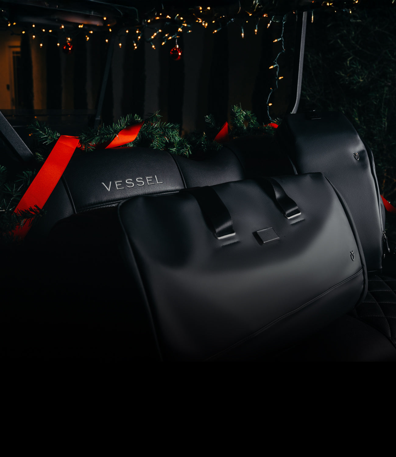 Black leather VESSEL Duffel sitting in a black golf cart, Christmas decorations