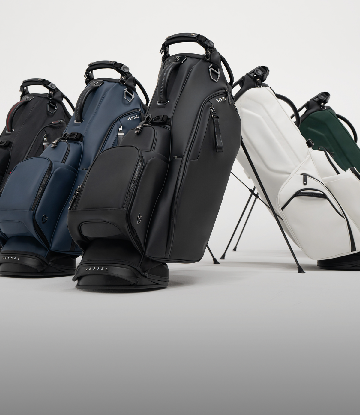 Five player VI stand leather golf bags lined up against a white background