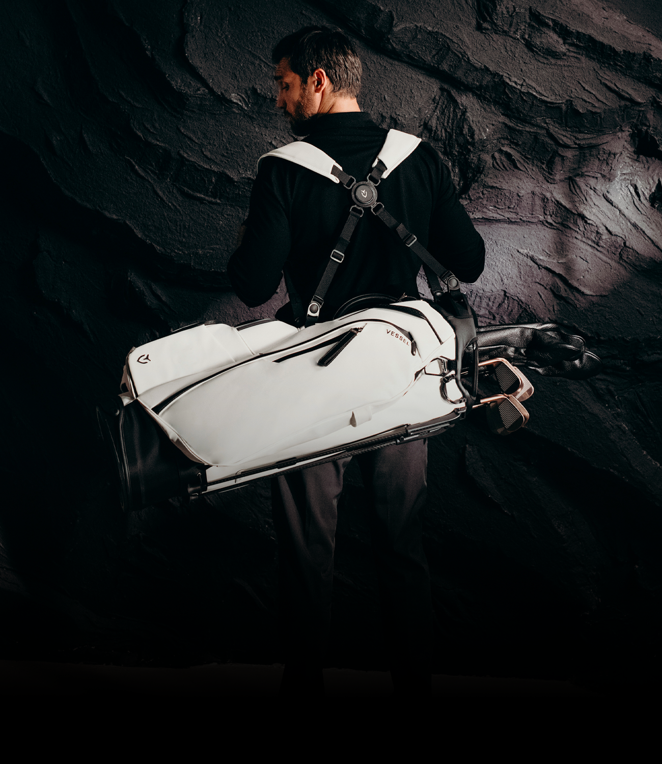Man in black shirt wearing white leather golf bag on his back