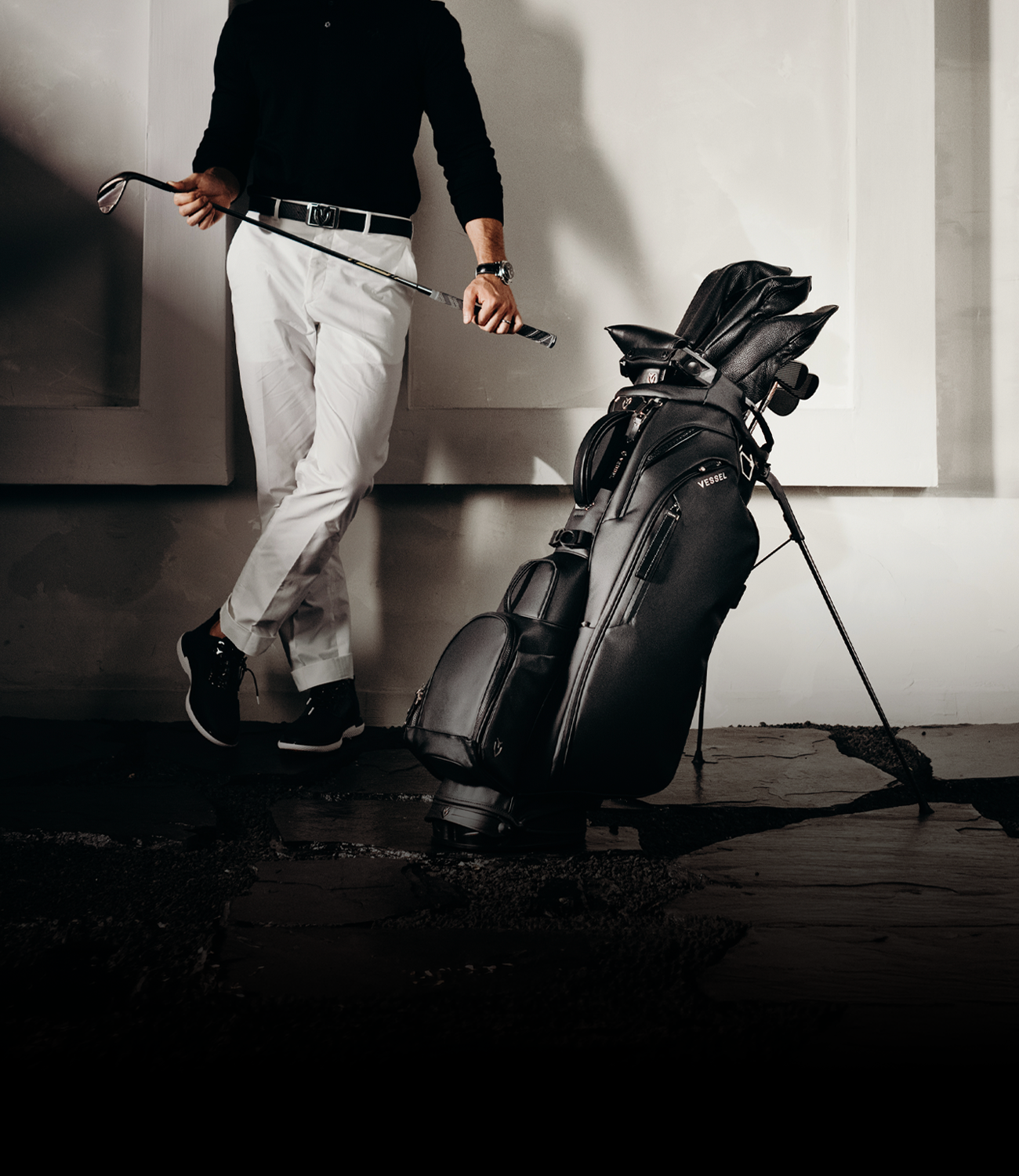 black leather golf bag next to man in golf pants