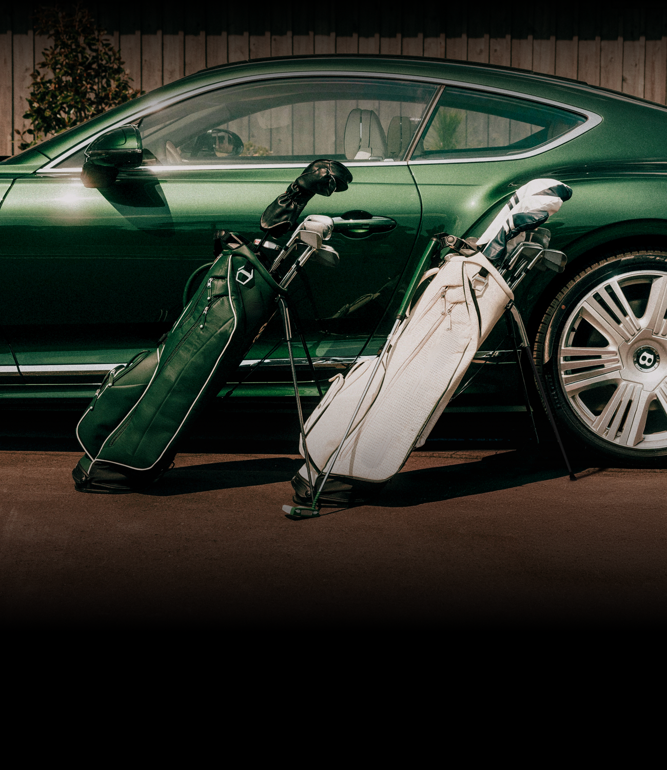 Two leather golf bags in front of a green bentley