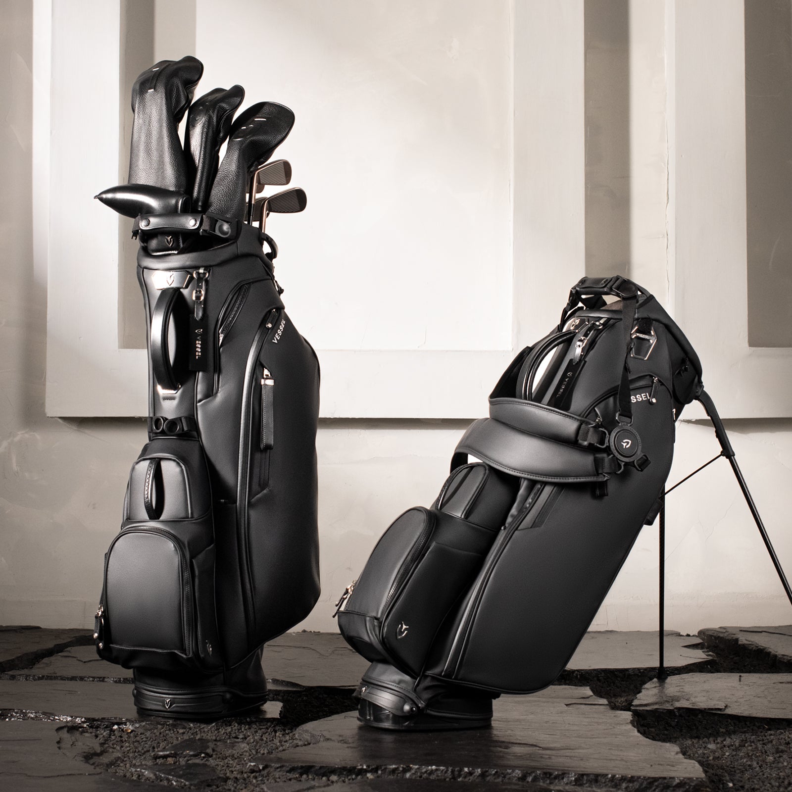 Two black golf bags with clubs against a neutral background