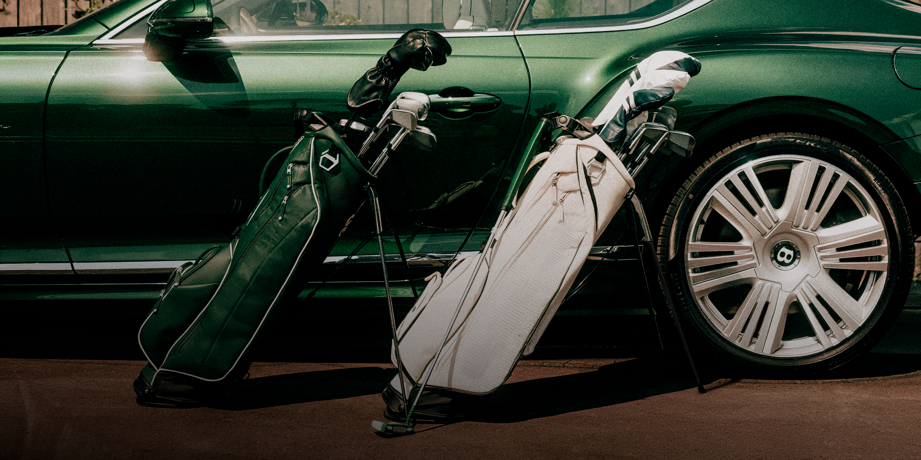Two leather golf bags in front of a green bentley