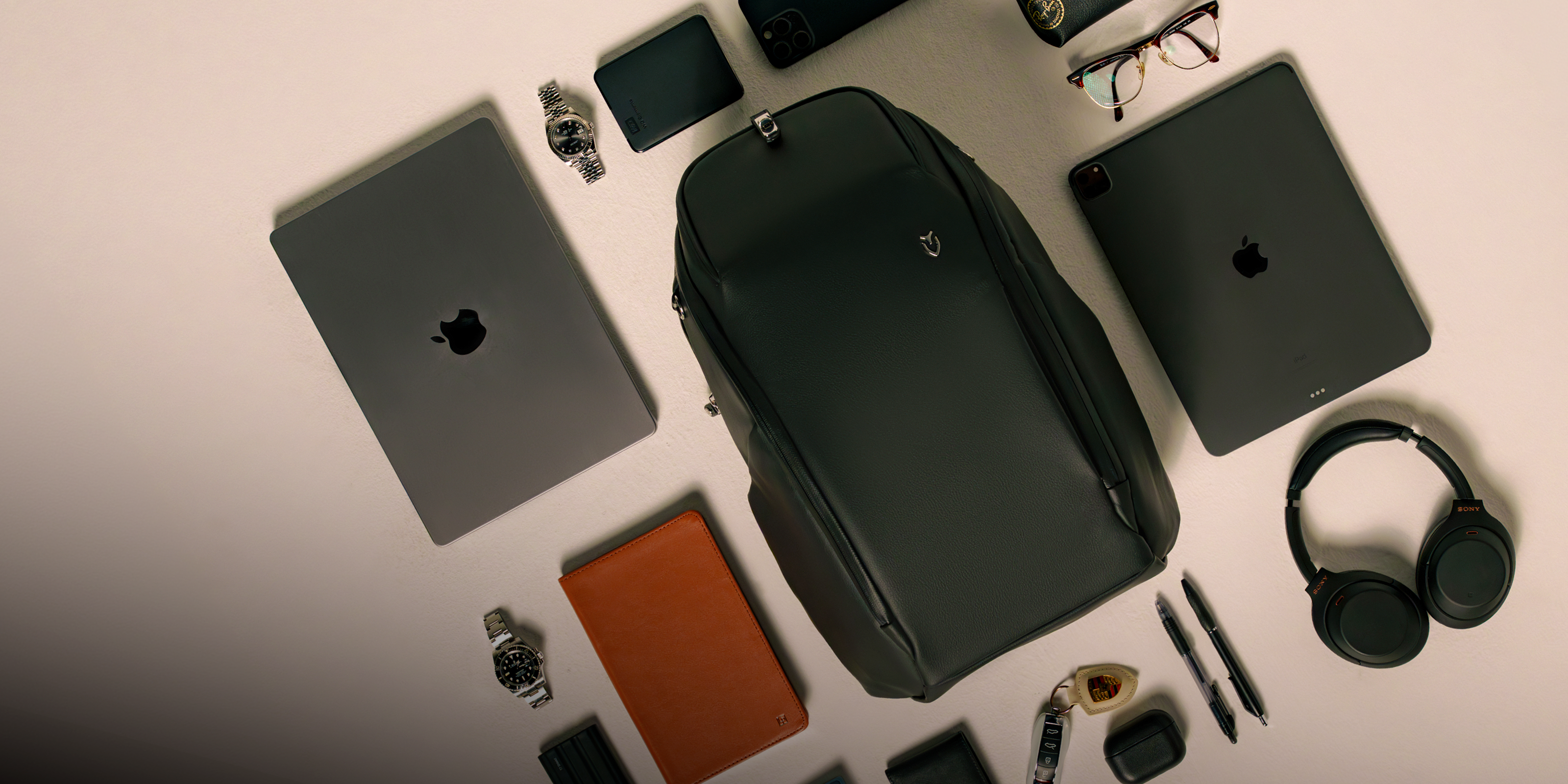 Black travel backpack with everyday items laying around it