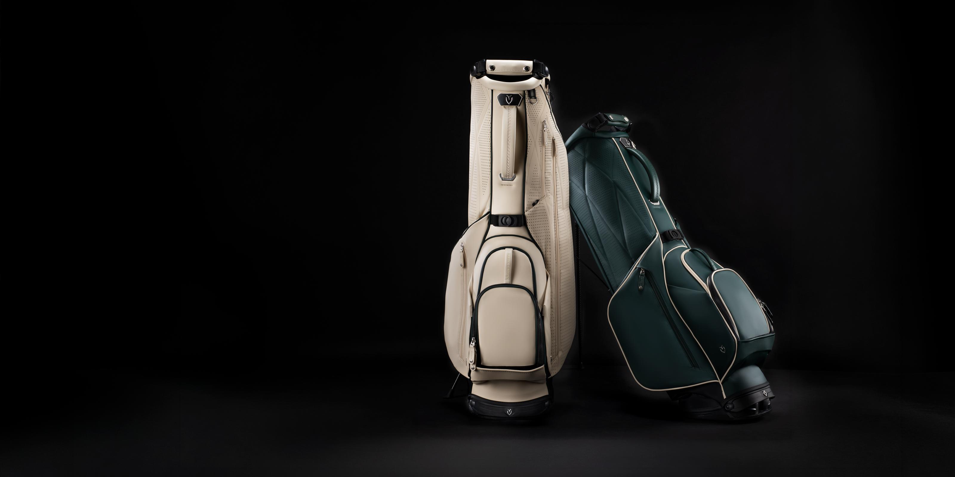 Two leather golf bags leaning against each other on a dark background
