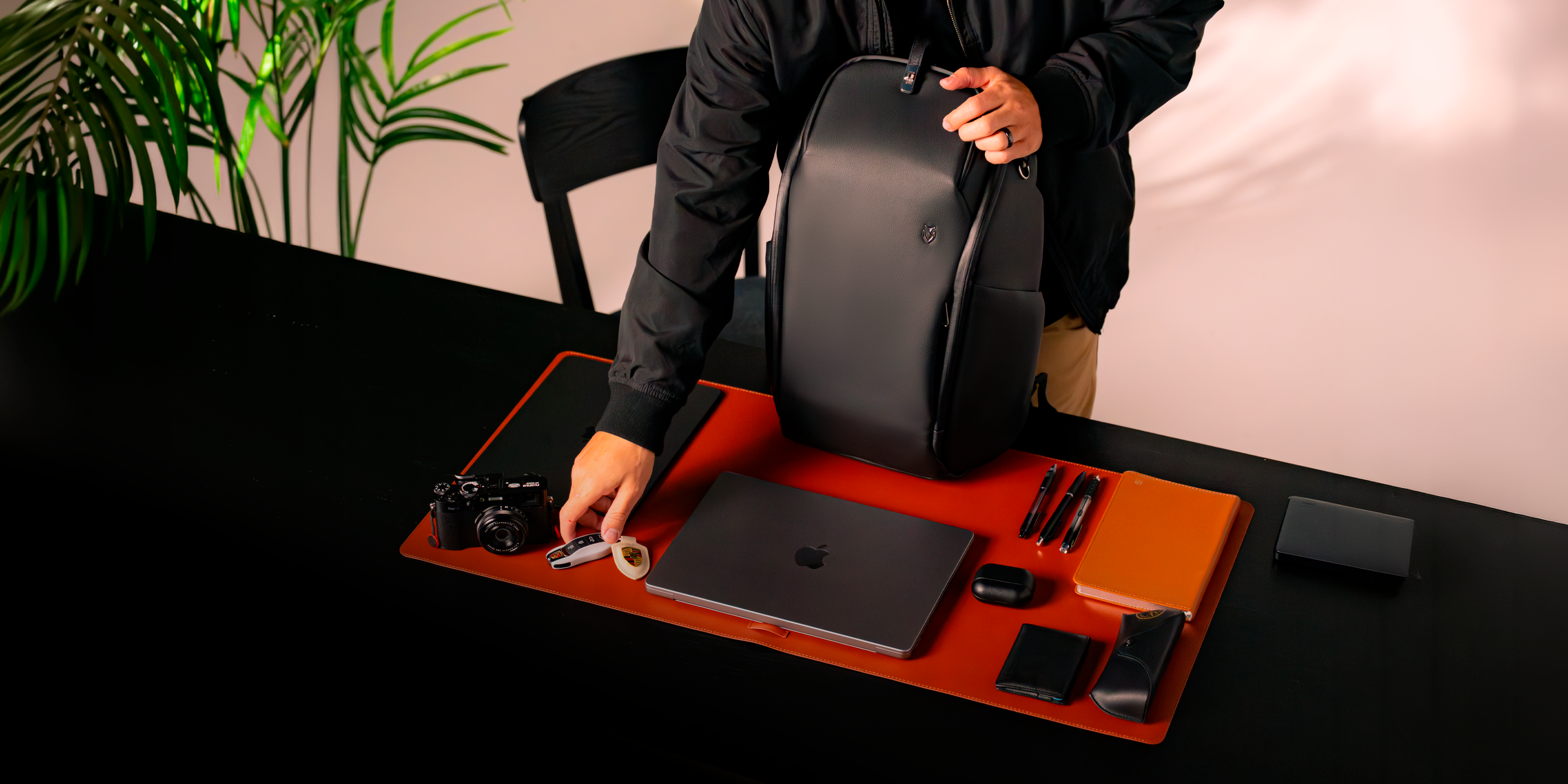 Black leather travel backpack on a desk with a man