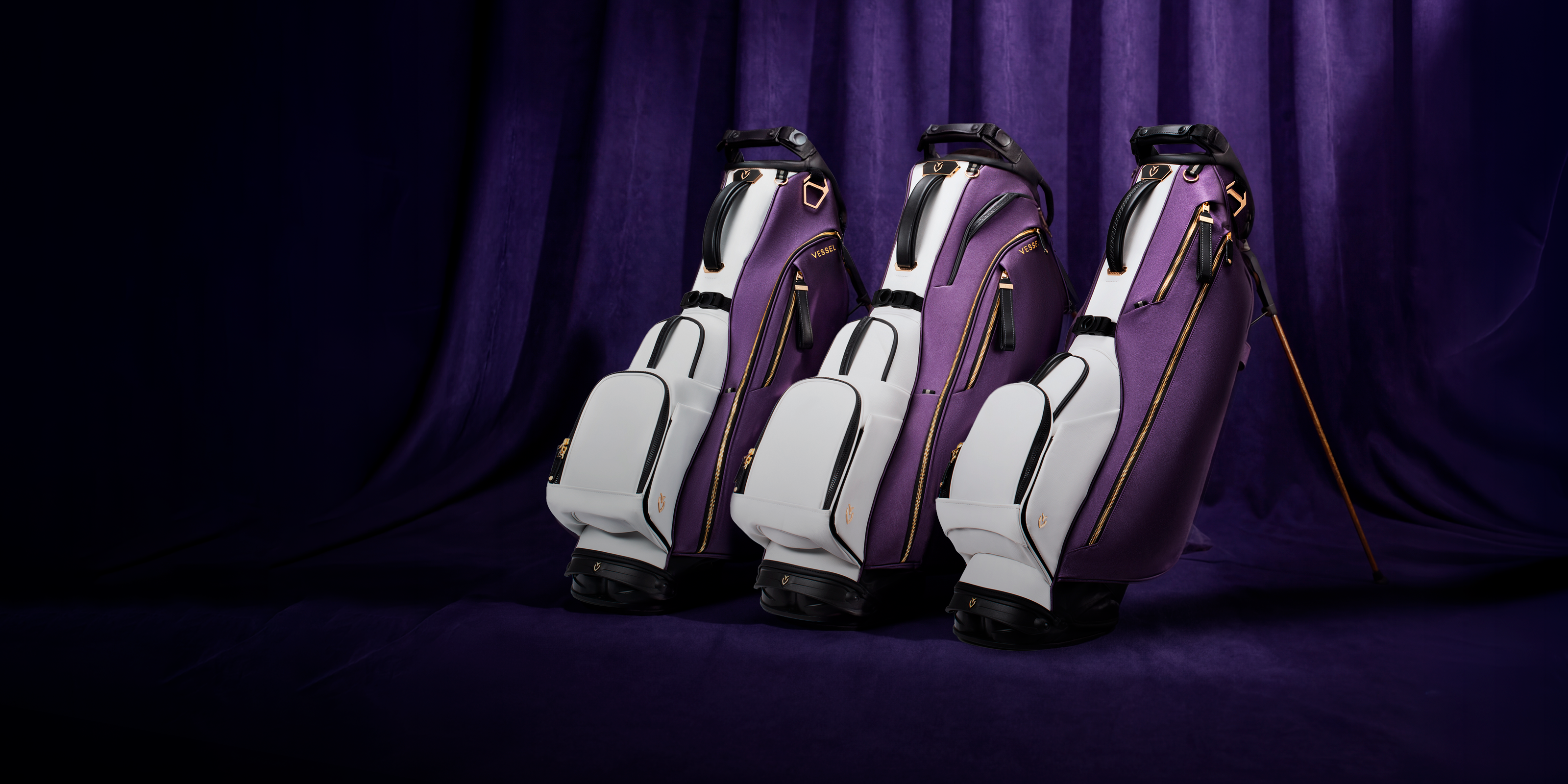 Three leather golf bags in front of a purple curtain
