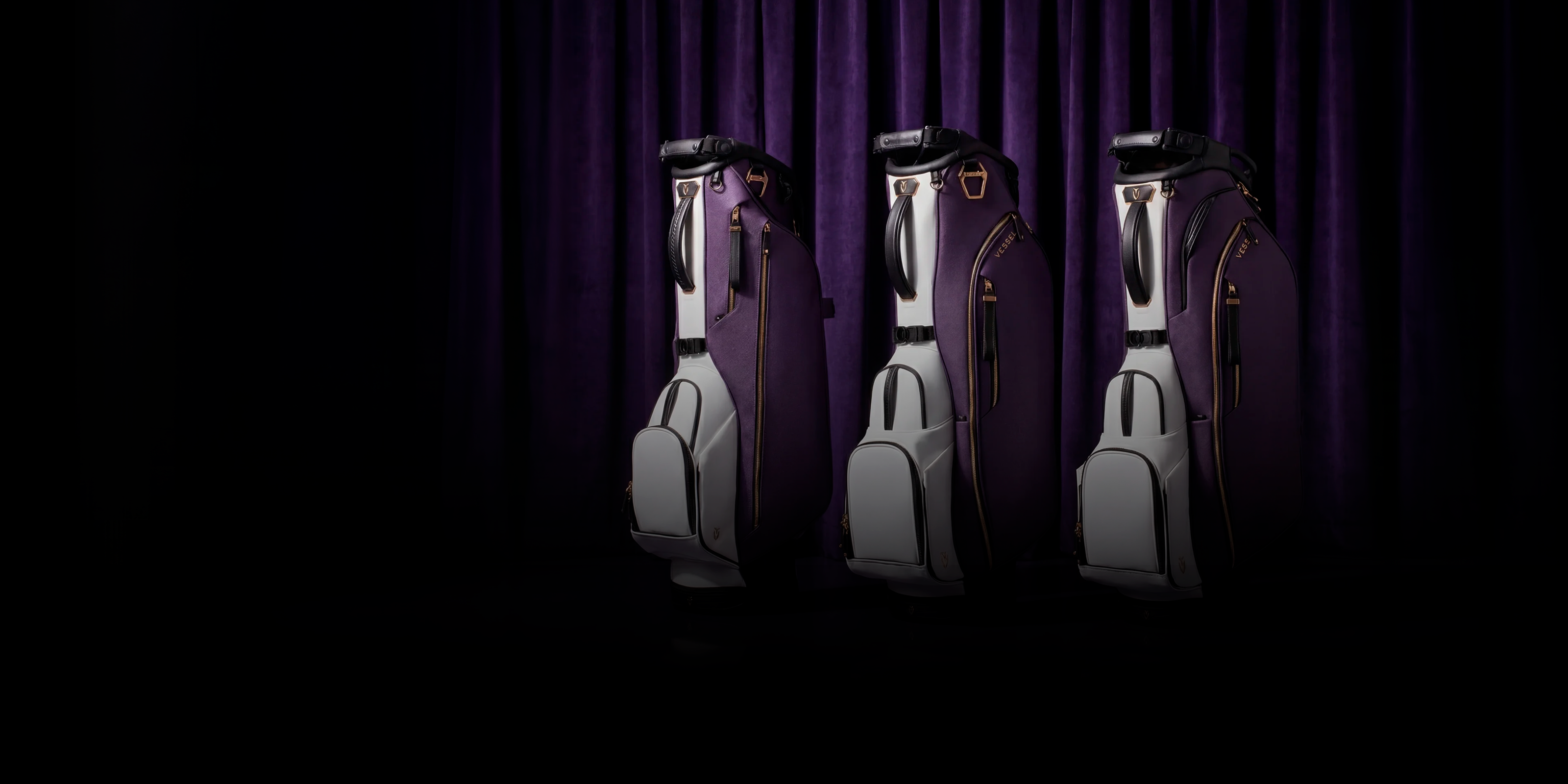 Three purple leather golf bags in front of a dark purple curtain