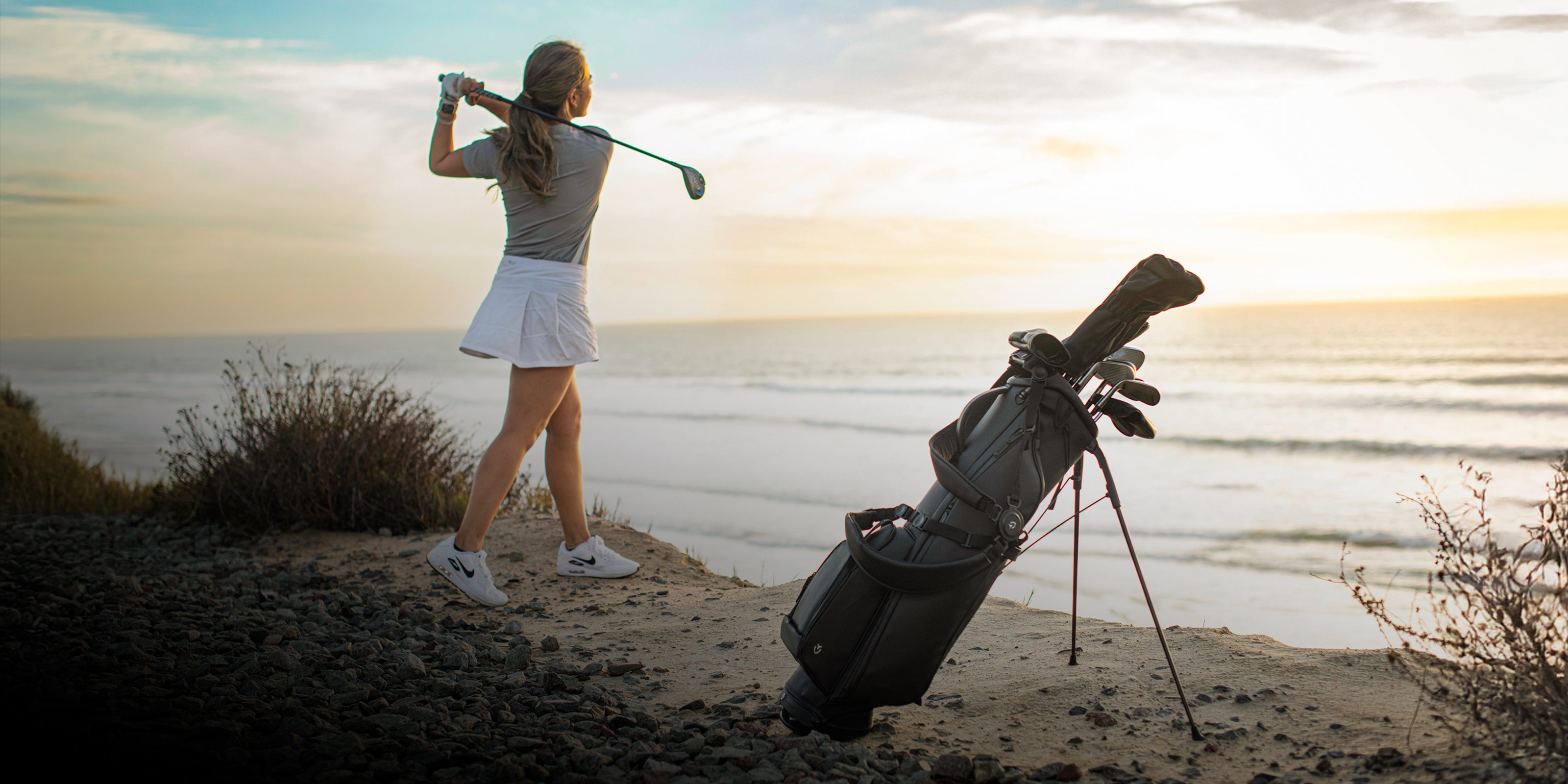 Woman with golf club on a beach next to Sunday III bag