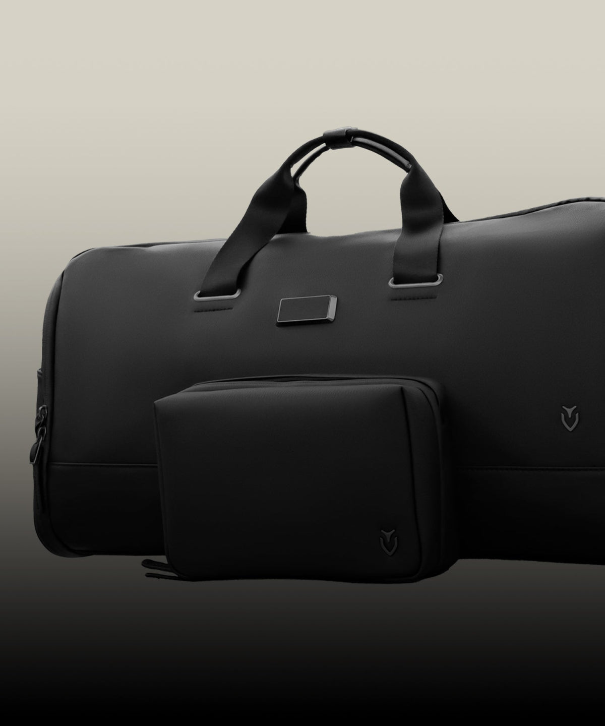 Black duffel bag and travel pouch on a taupe background