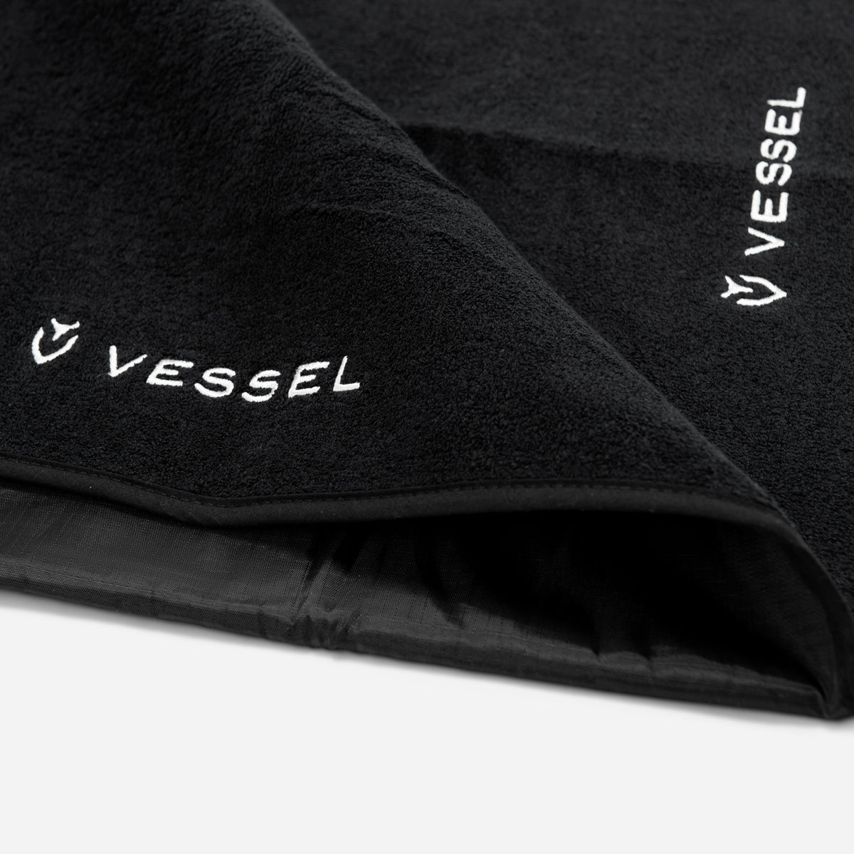 Close up of soft texture of black rainhood towel and embroidered Vessel logo