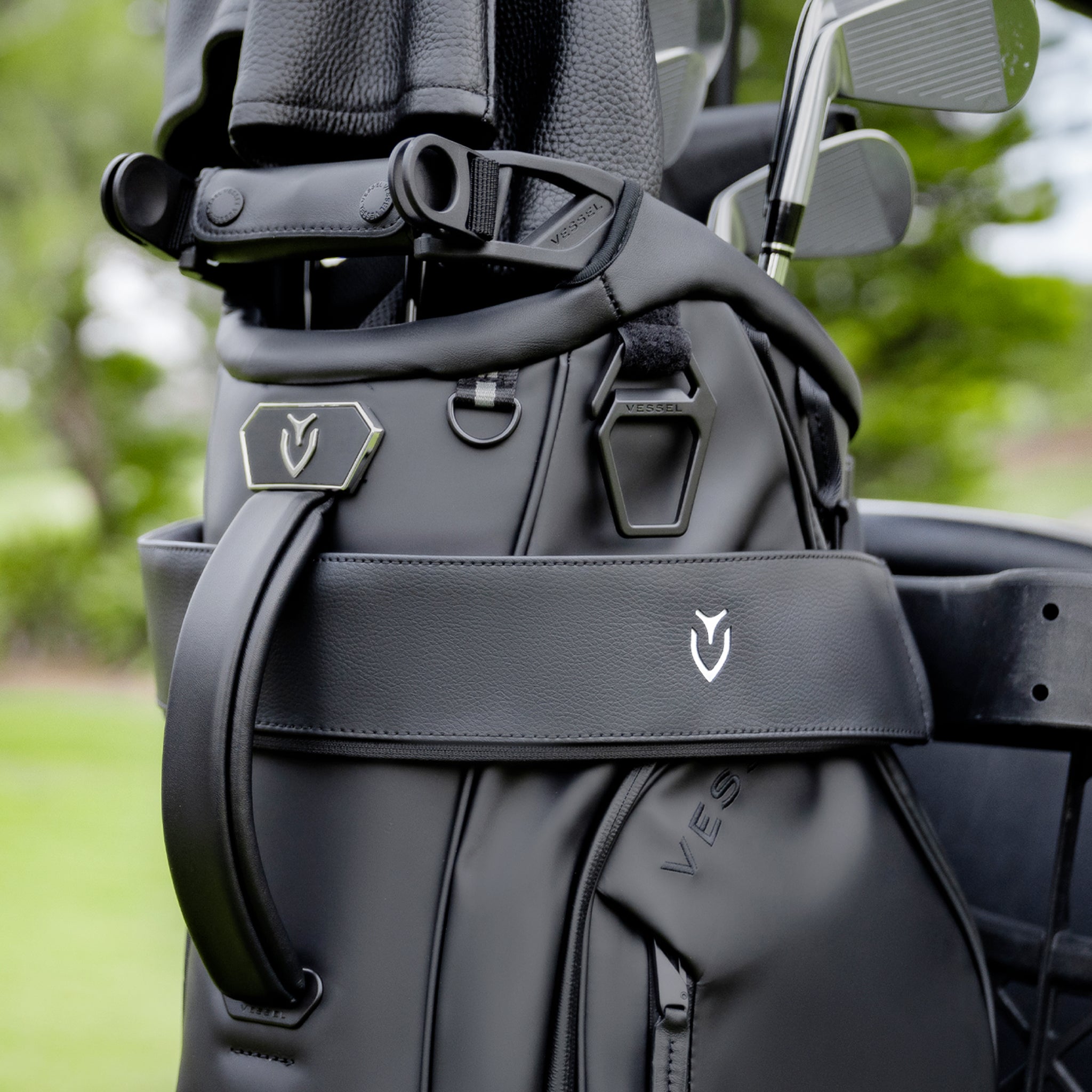 Black golf bag strapped into a golf cart with a black cart strap sleeve