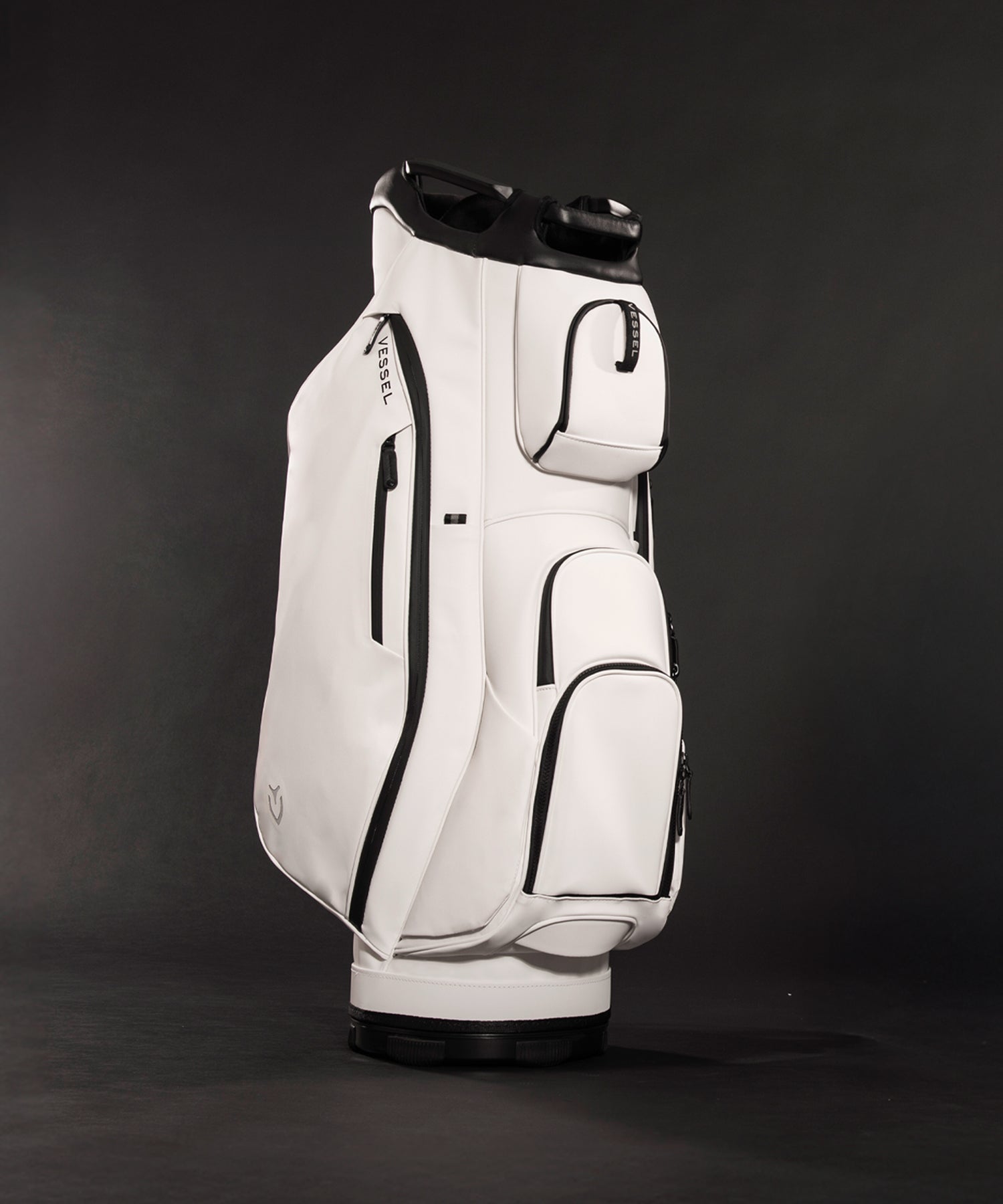 White leather golf cart bag standing in a dark grey room