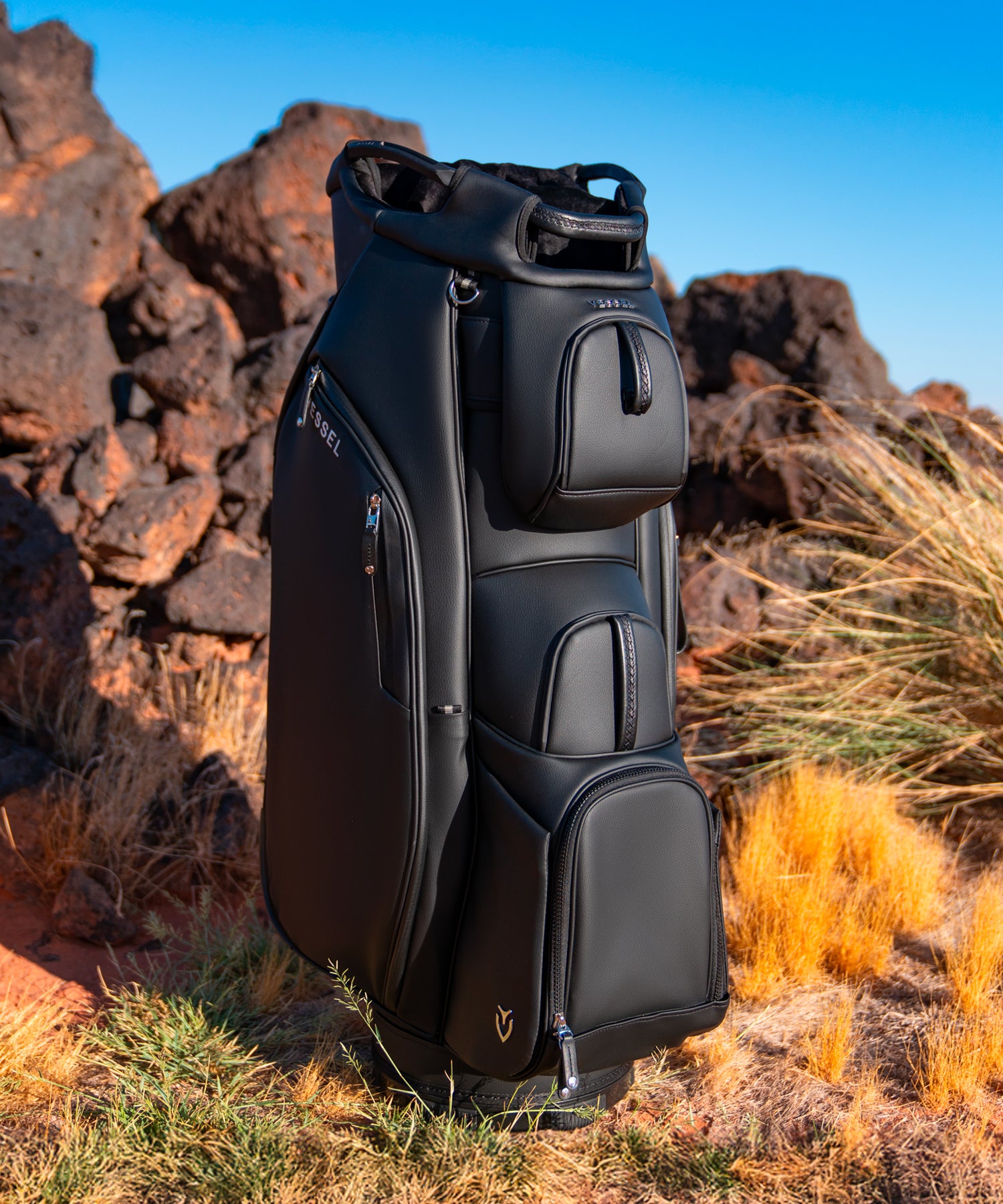 Black leather golf cart bag standing in a rocky desert
