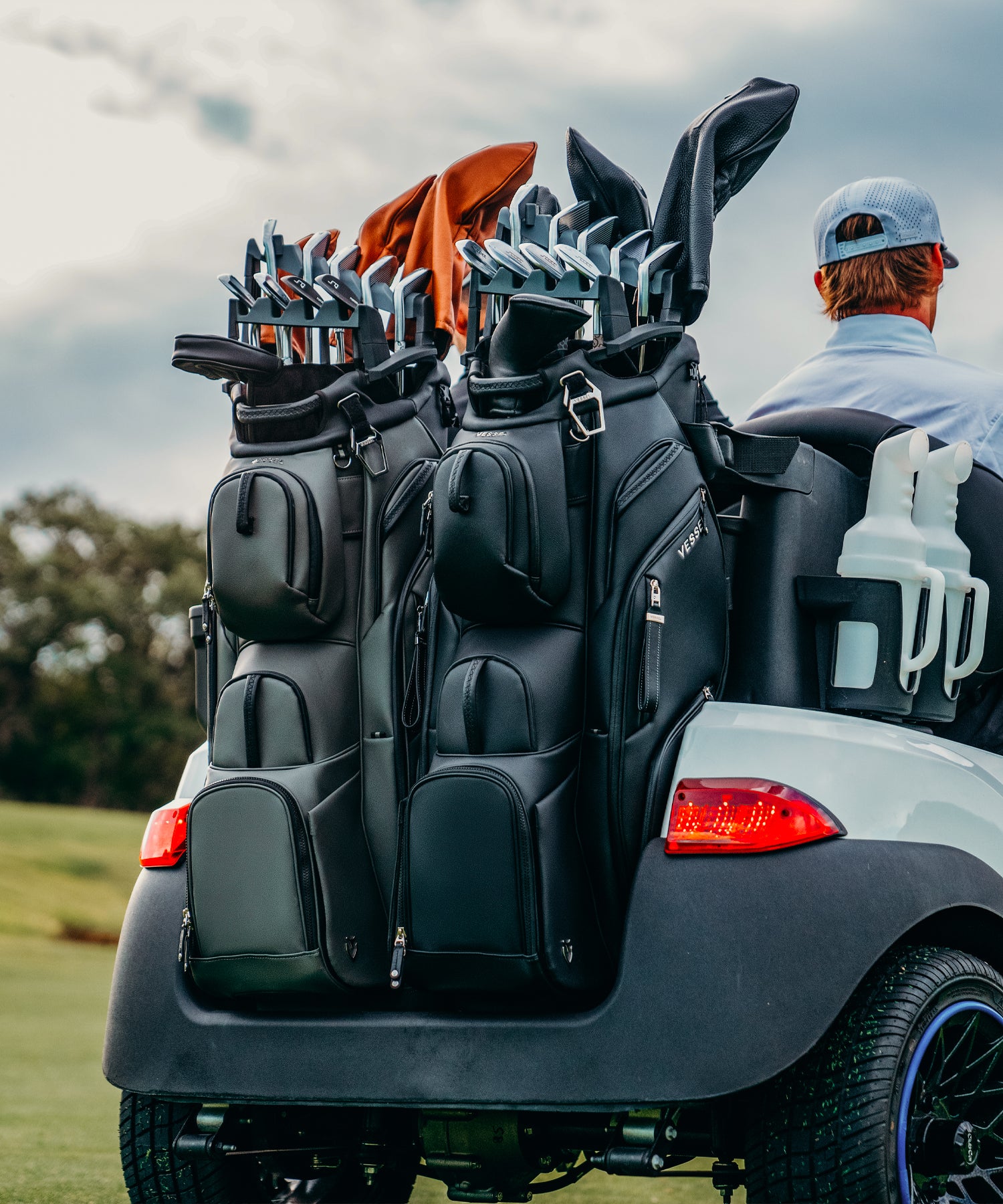 Two leather golf cart bags both filled with clubs in a golf club organizer on the back of a golf cart