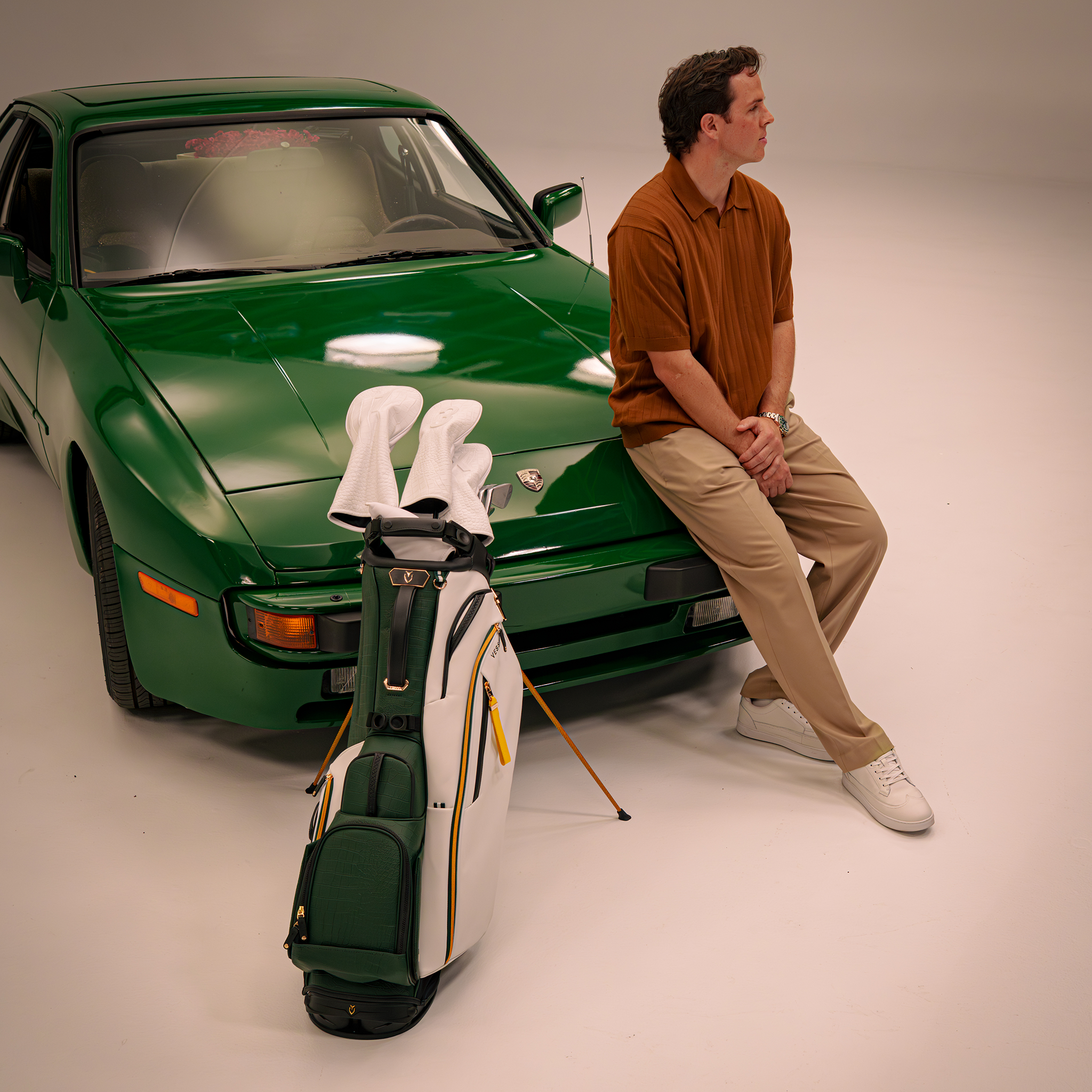 Man sitting next to 2026 Season Opener Player V Pro Stand and green porsche