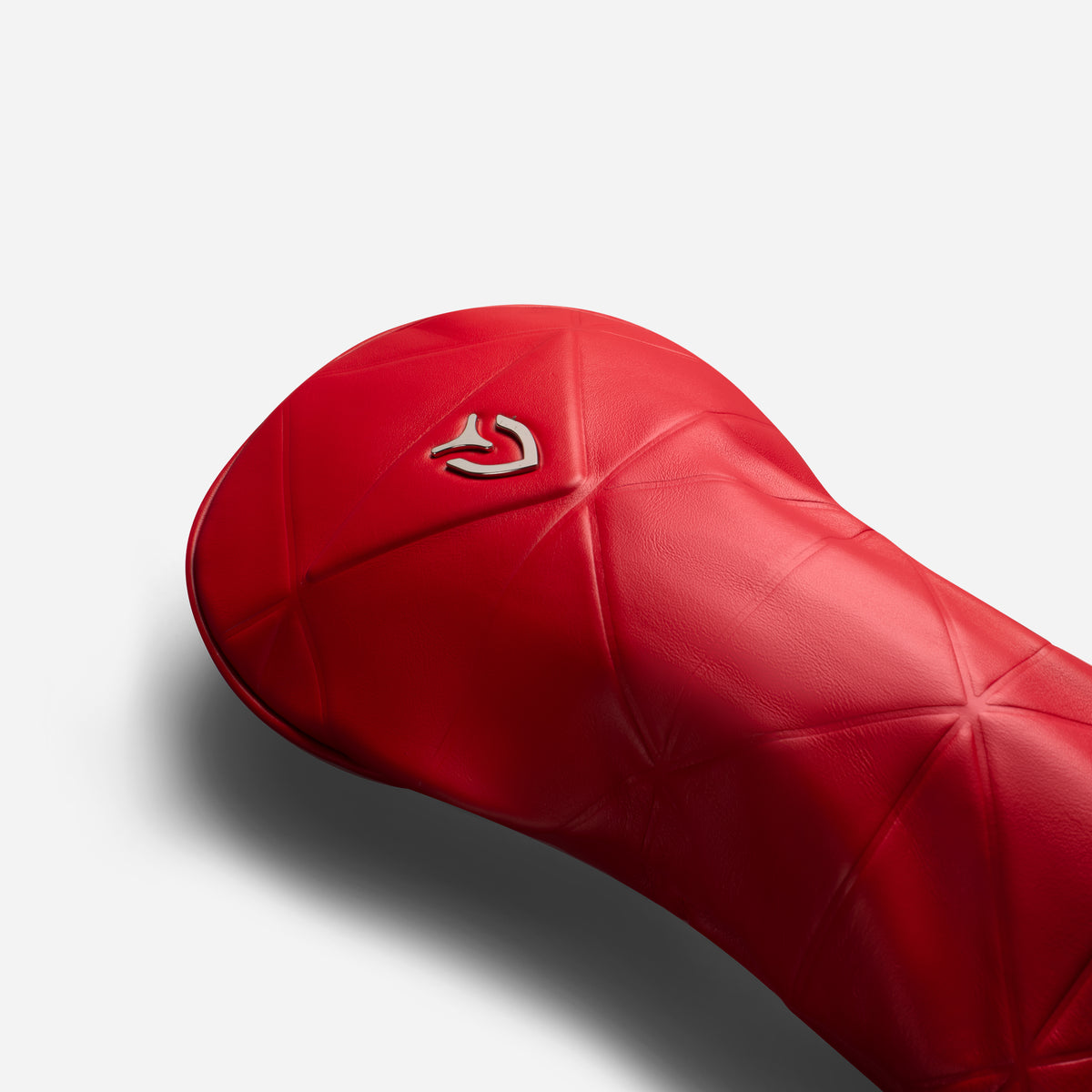 Close up of metal logo on red geometric headcover on a white background