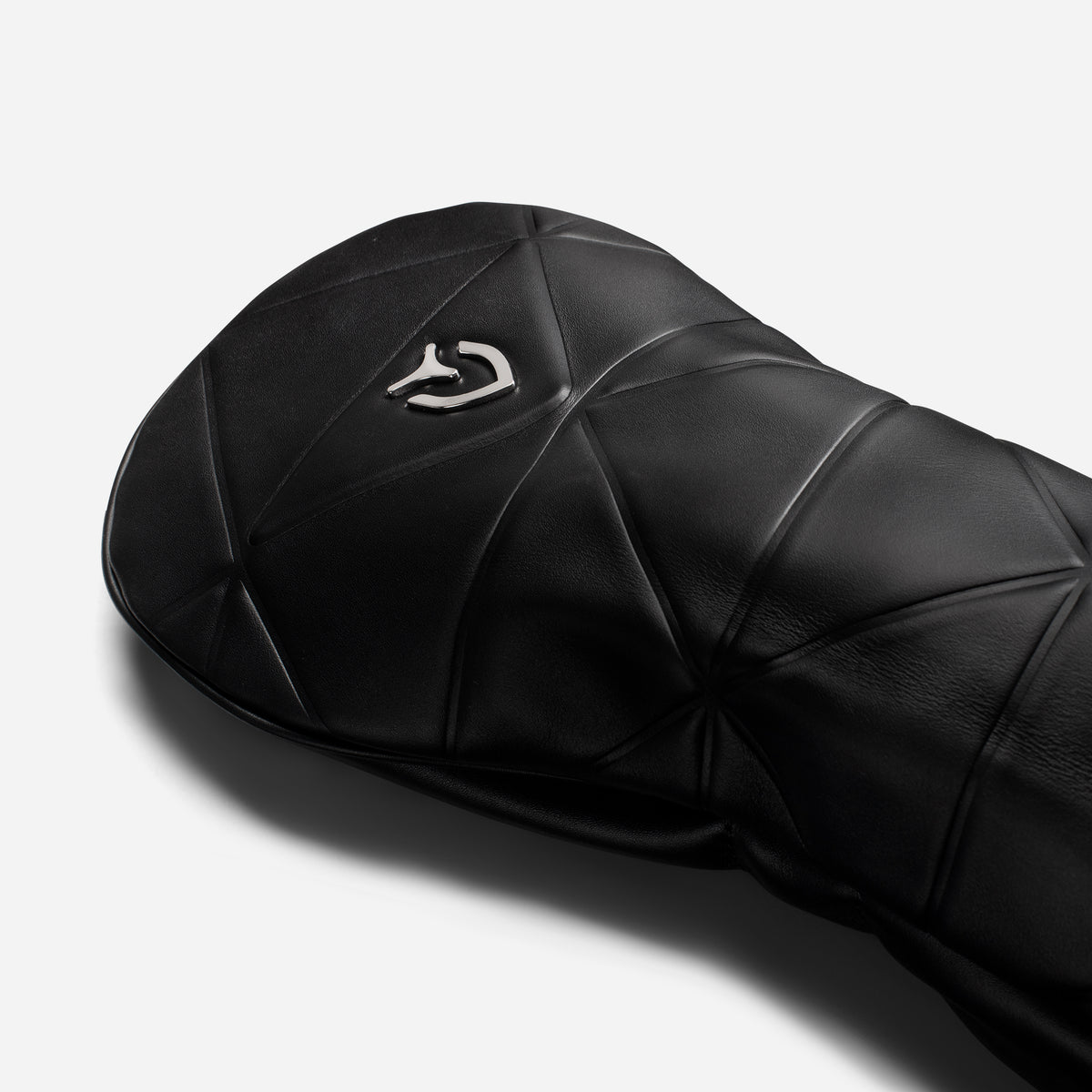 Close up of metal logo on black geometric headcover on a white background