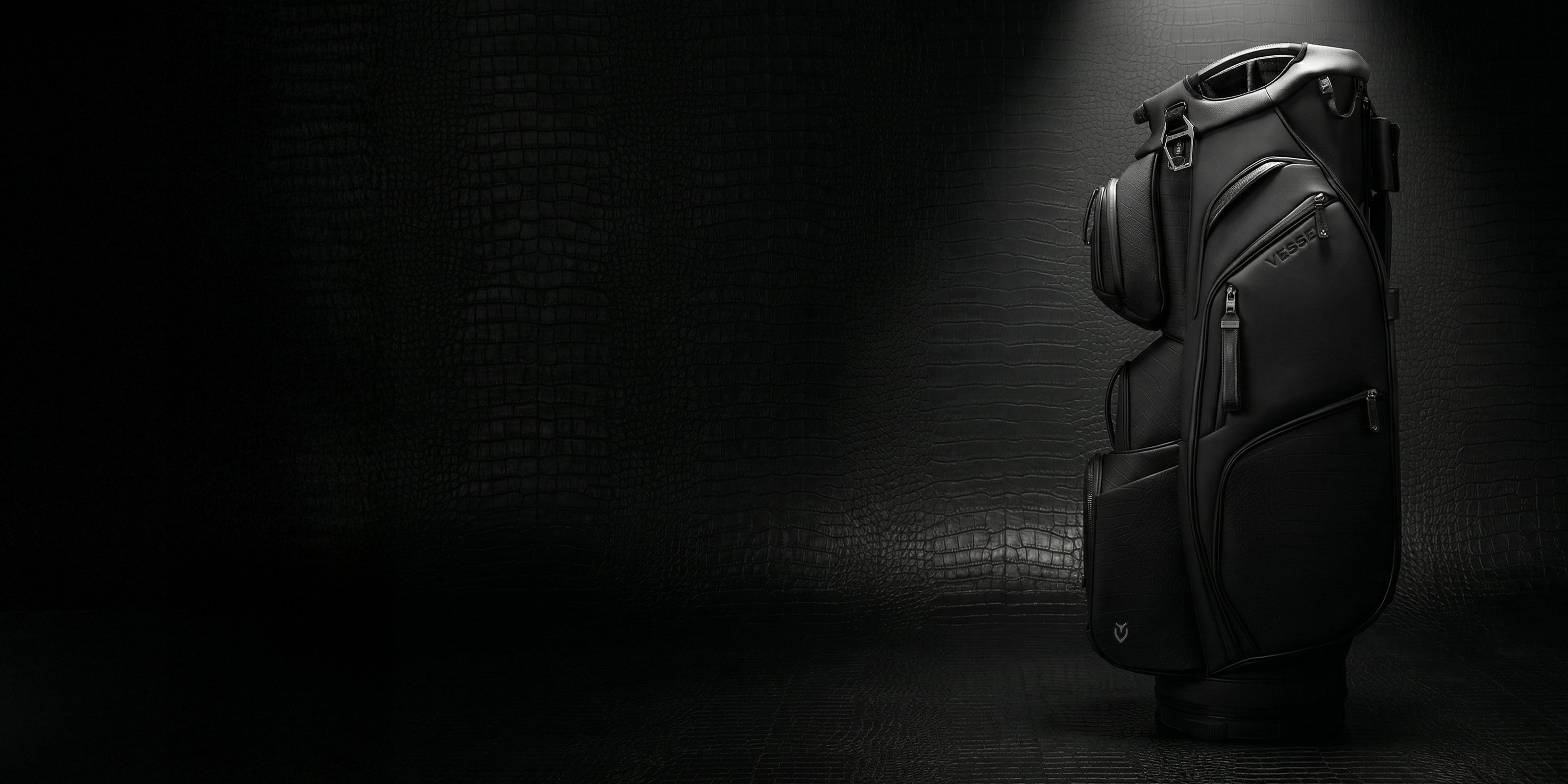 Black leather golf bag against a crocodile leather background
