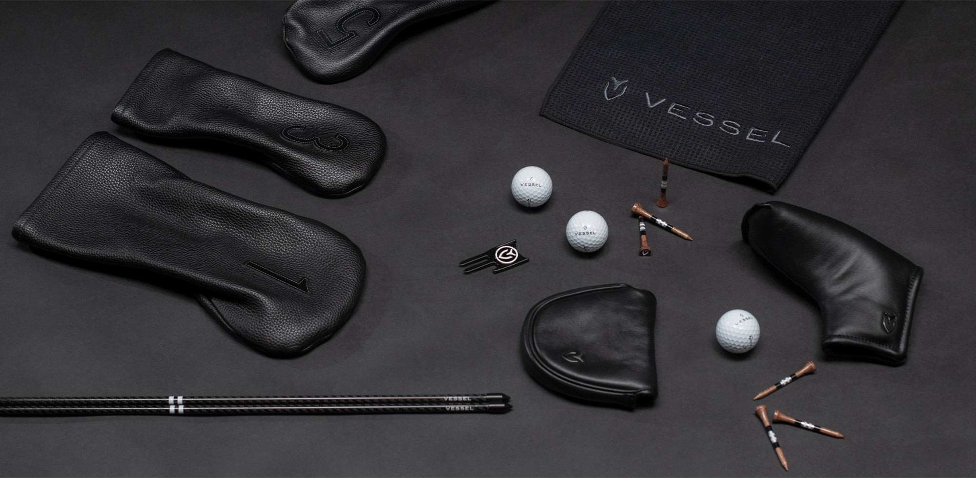 Black golf leather headcovers, Black magnetic golf towel, golf tees, golf balls, a divot tool, and black alignment sticks.
