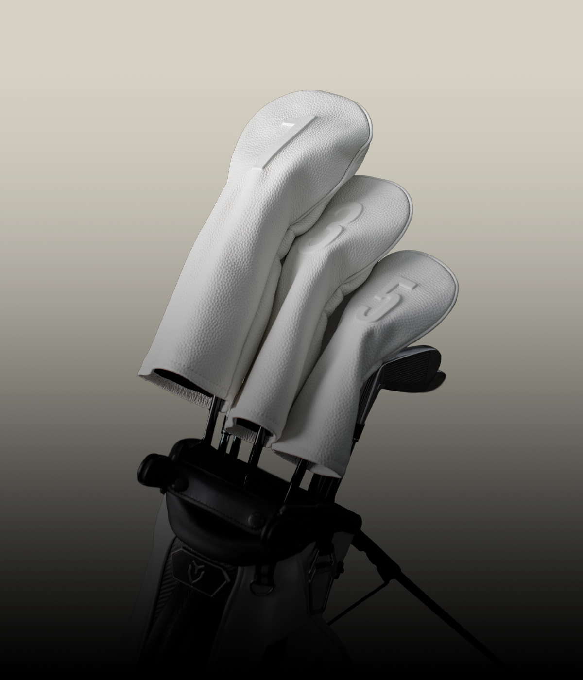 White pebbled leather golf club headcovers against a taupe background