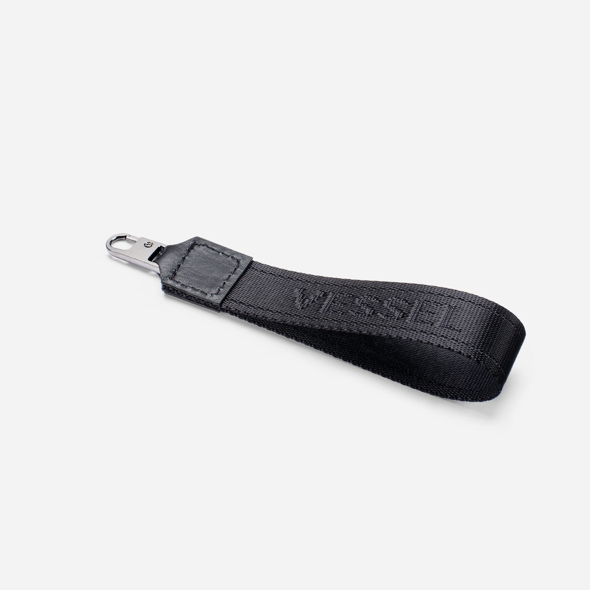 Black jacquard fabric loop zipper pull against a white background at an angle
