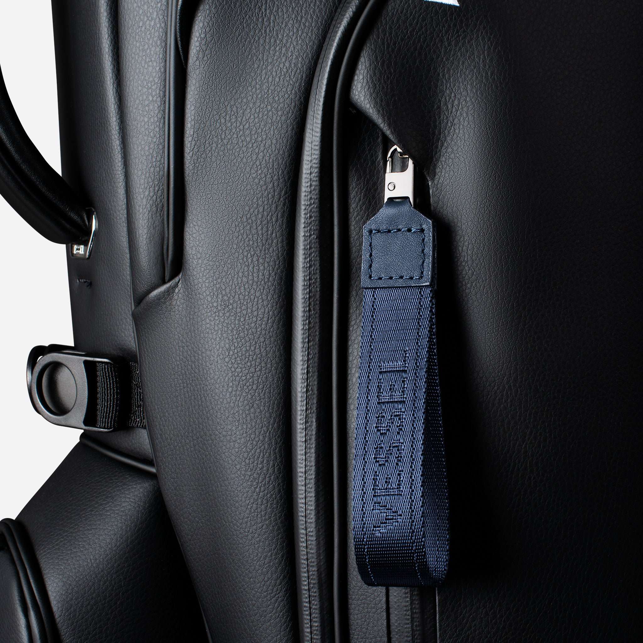 Navy jacquard fabric loop zipper pull attached to a black leather golf bag